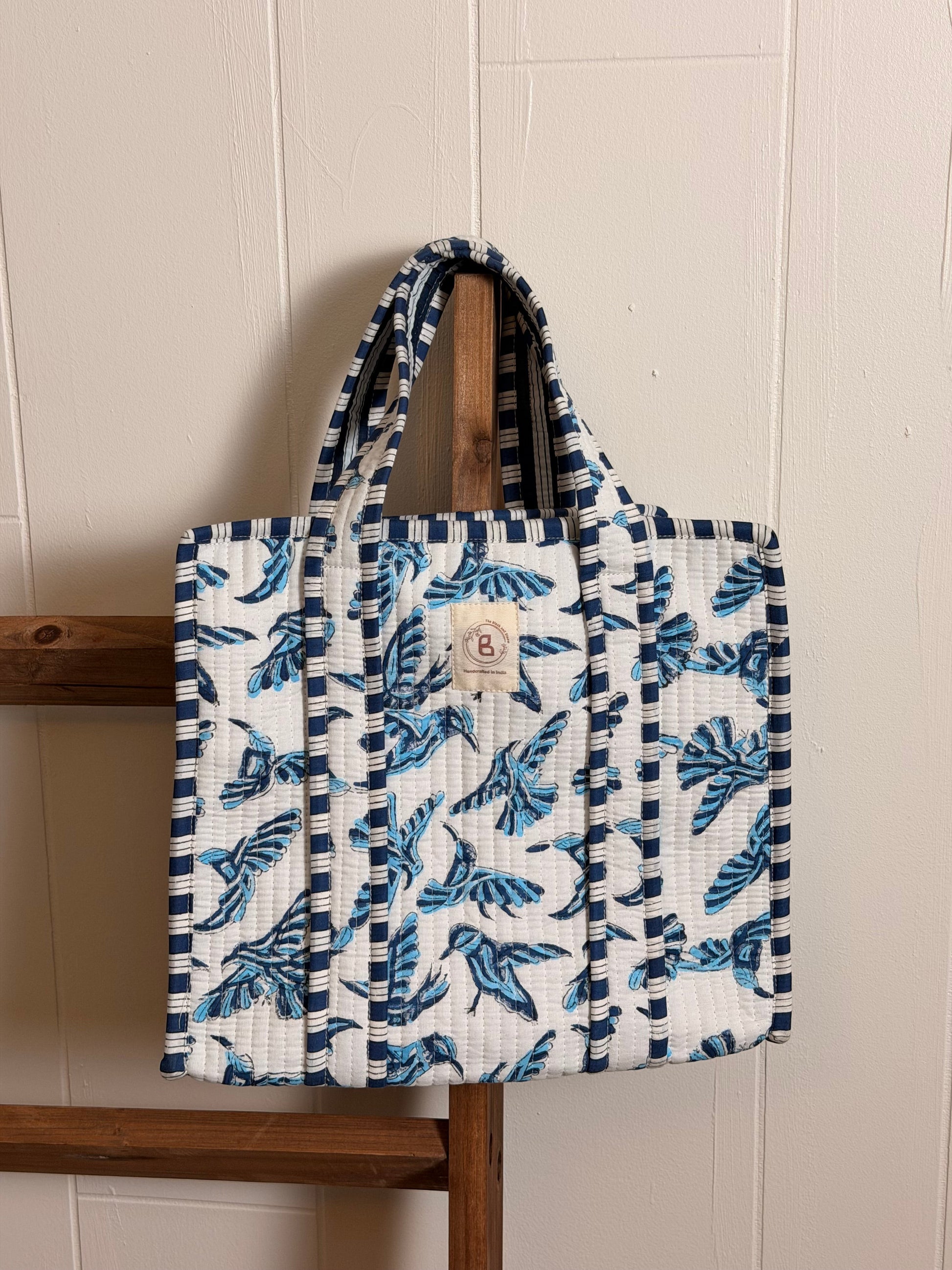 The Block & Bloom mini quilted tote featuring a blue bird hand block print on white fabric with striped trim.