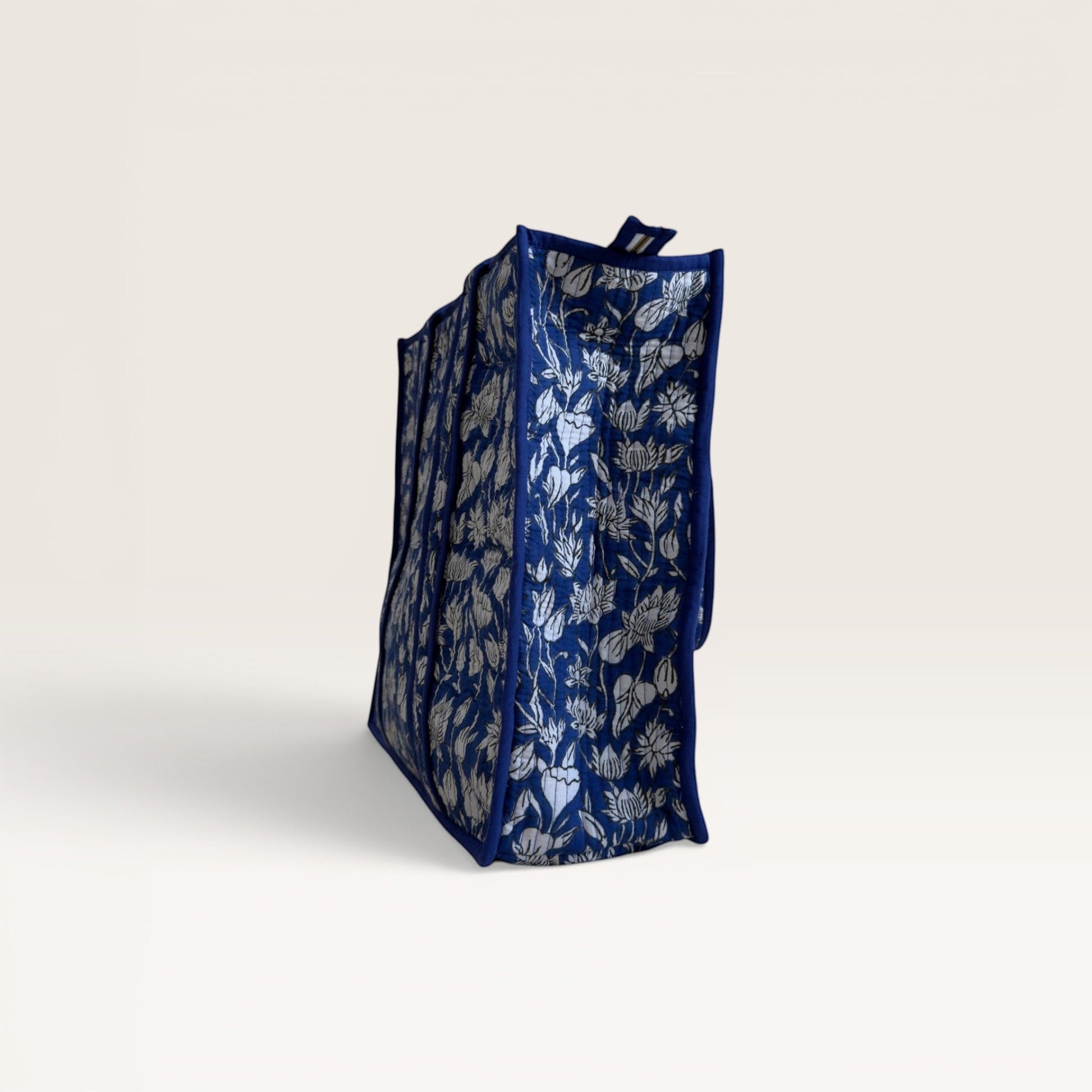 The Block & Bloom cobalt blue quilted tote bag with white hand block printed lotus flower patterns, side view.