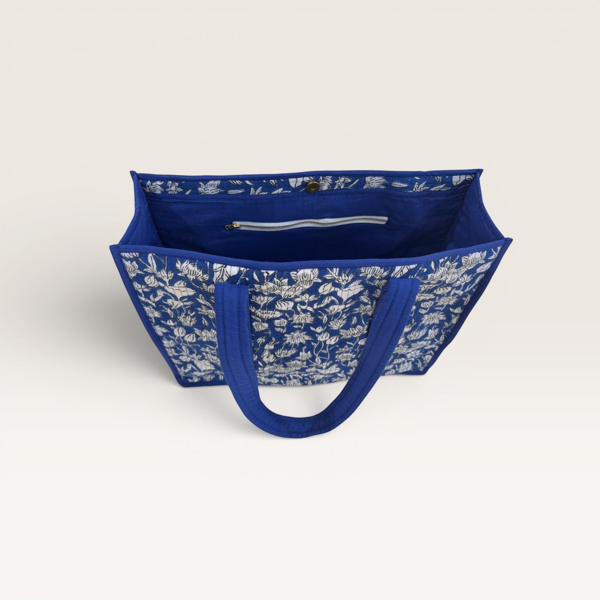 The Block & Bloom cobalt blue quilted tote bag with white hand-block printed lotus flowers and interior zip pocket.
