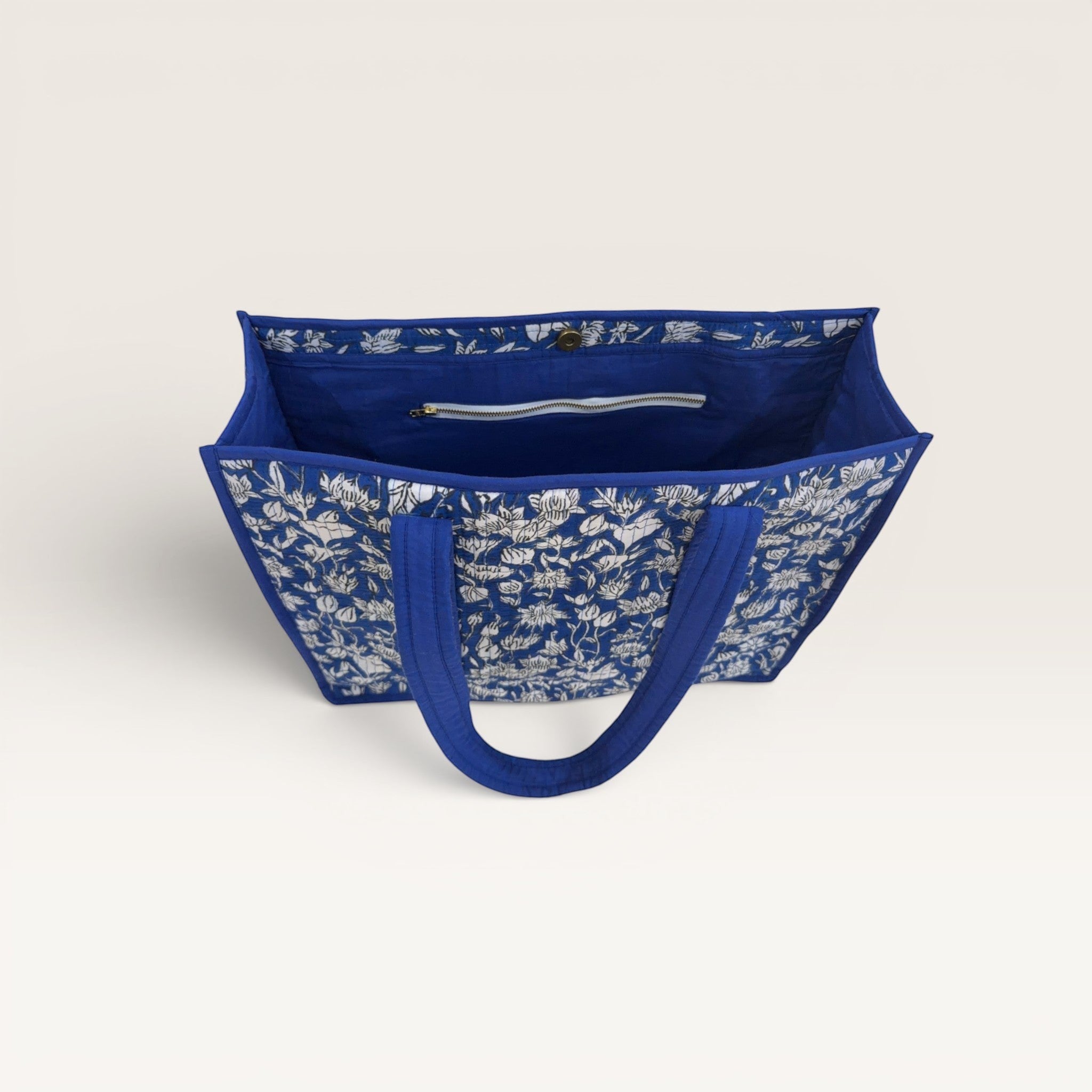 The Block & Bloom cobalt blue quilted tote bag with white hand-block printed lotus flowers and interior zip pocket.