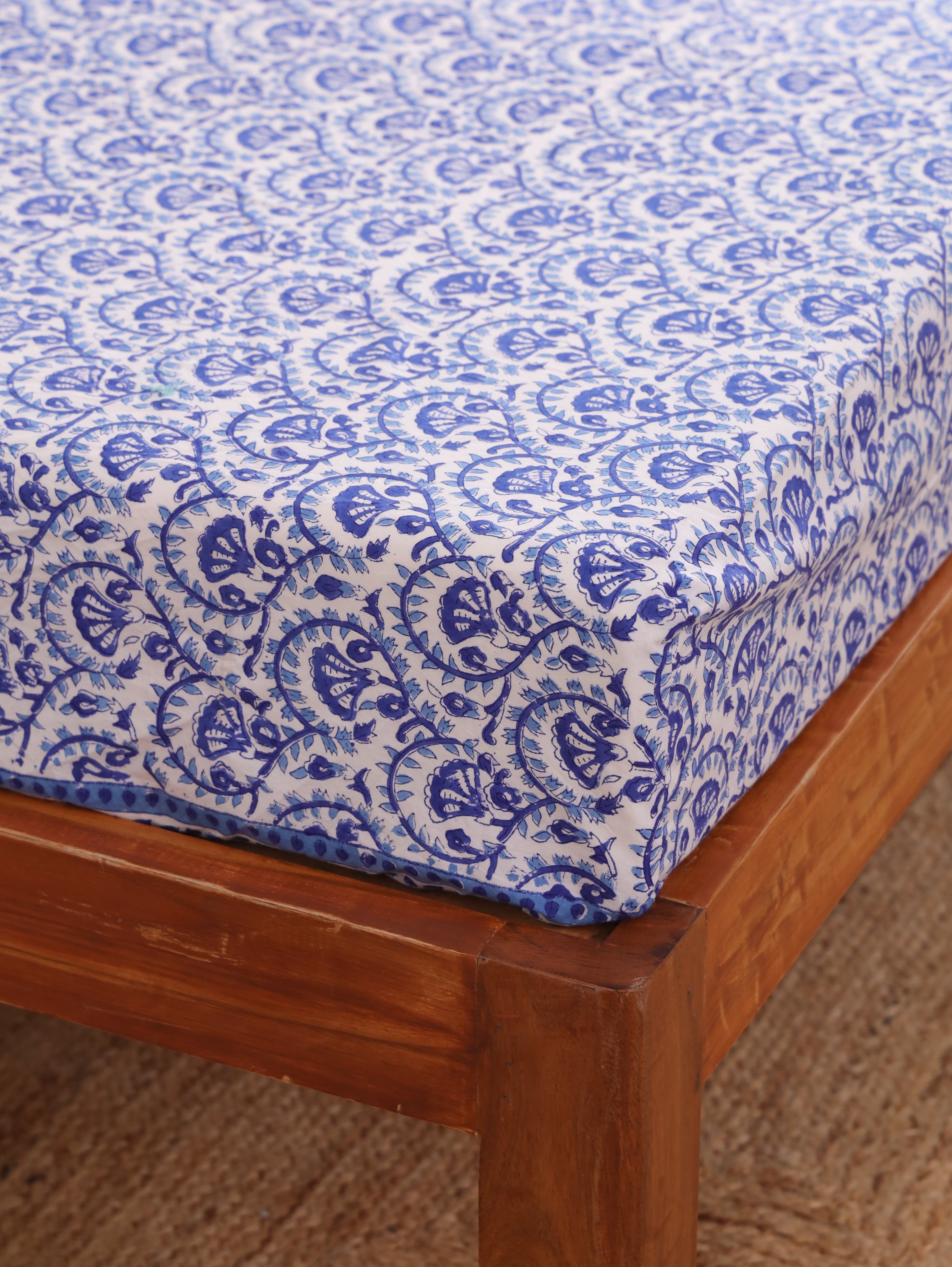 The Block & Bloom blue and white hand block printed cotton percale fitted bedsheet with a flowing vine pattern.