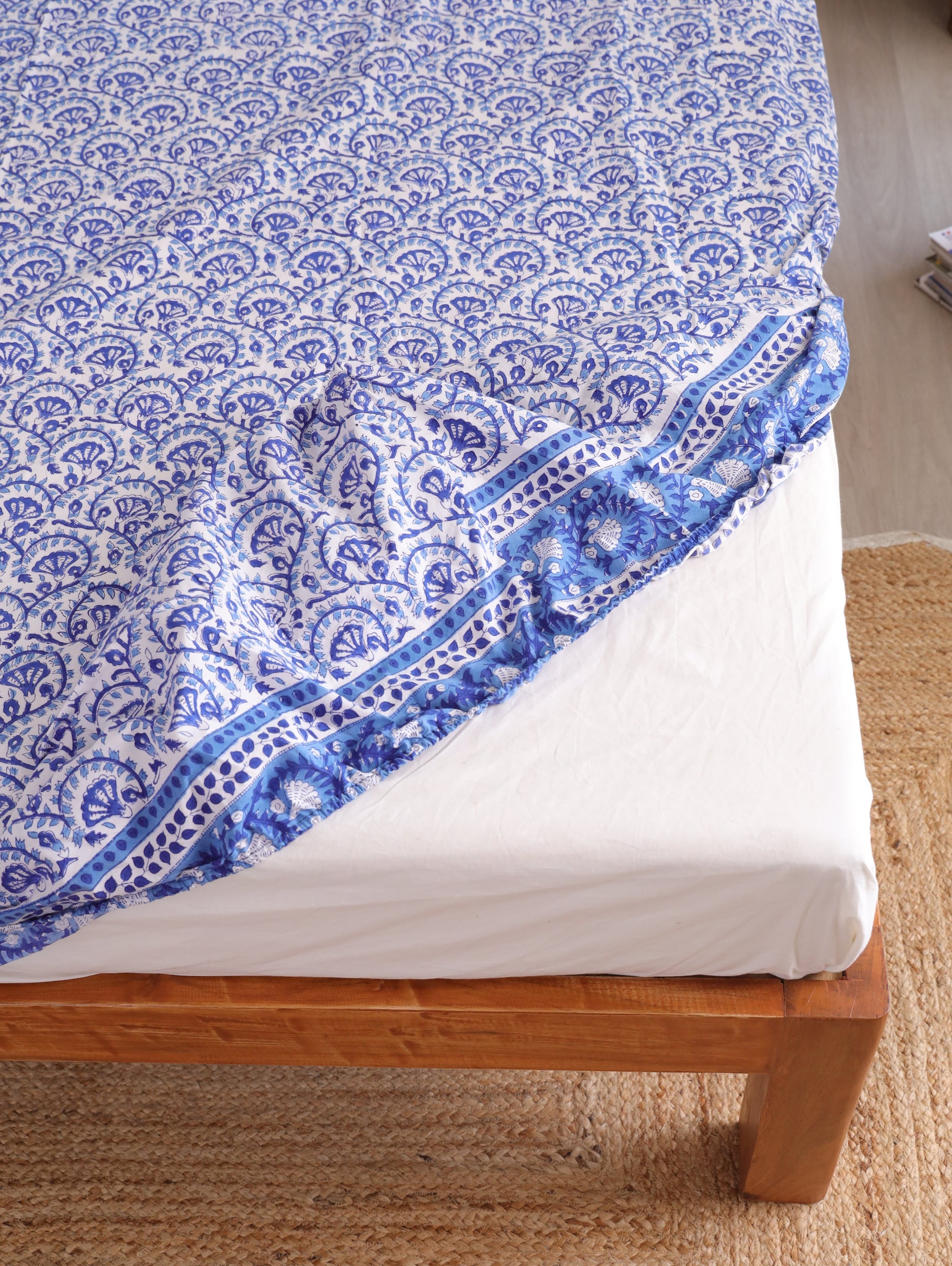 The Block & Bloom blue and white hand block printed cotton percale fitted bedsheet with a detailed vine fan pattern.