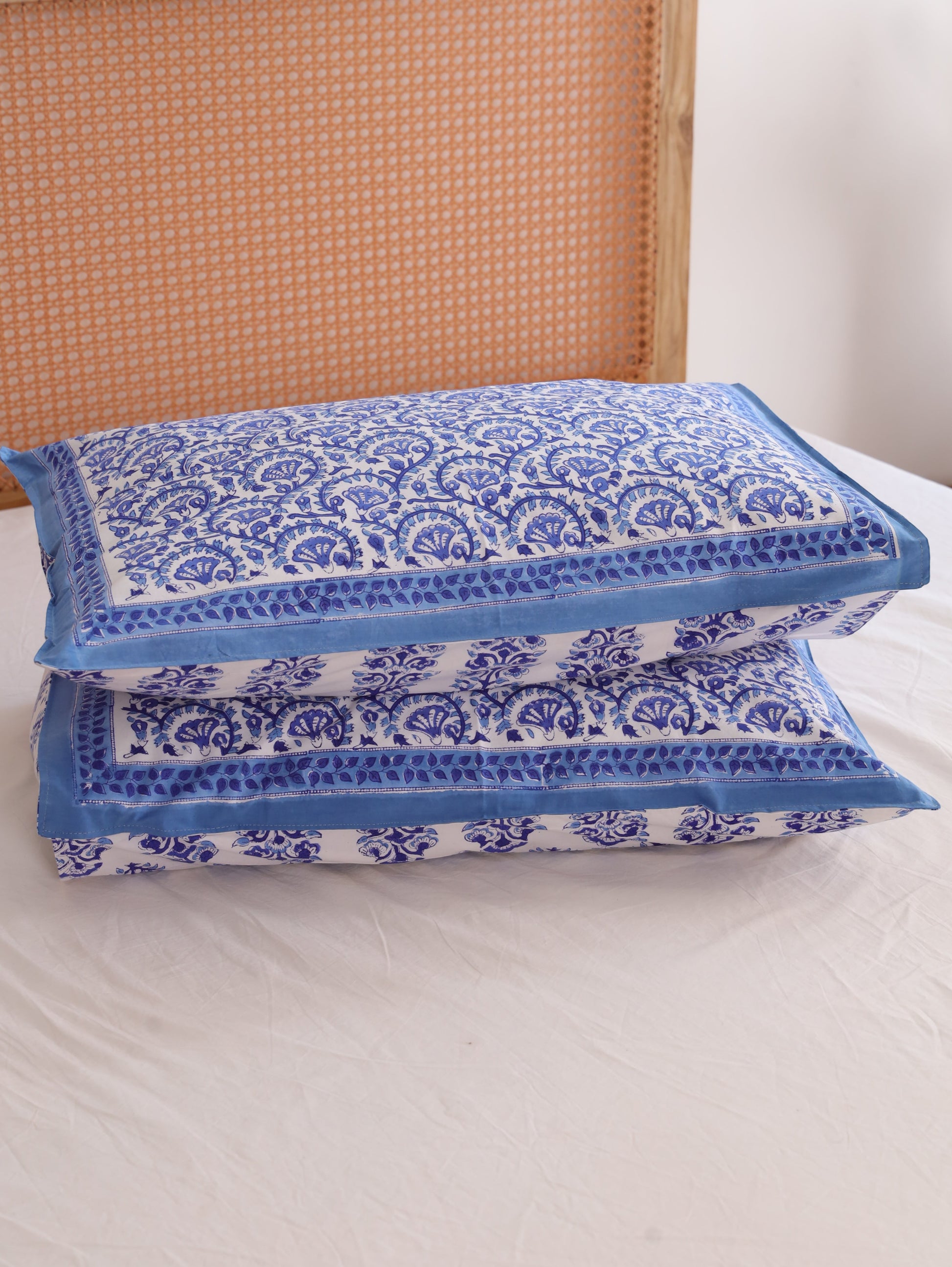 The Block & Bloom cotton pillowcases featuring a blue and white hand block printed vine pattern with solid blue borders.