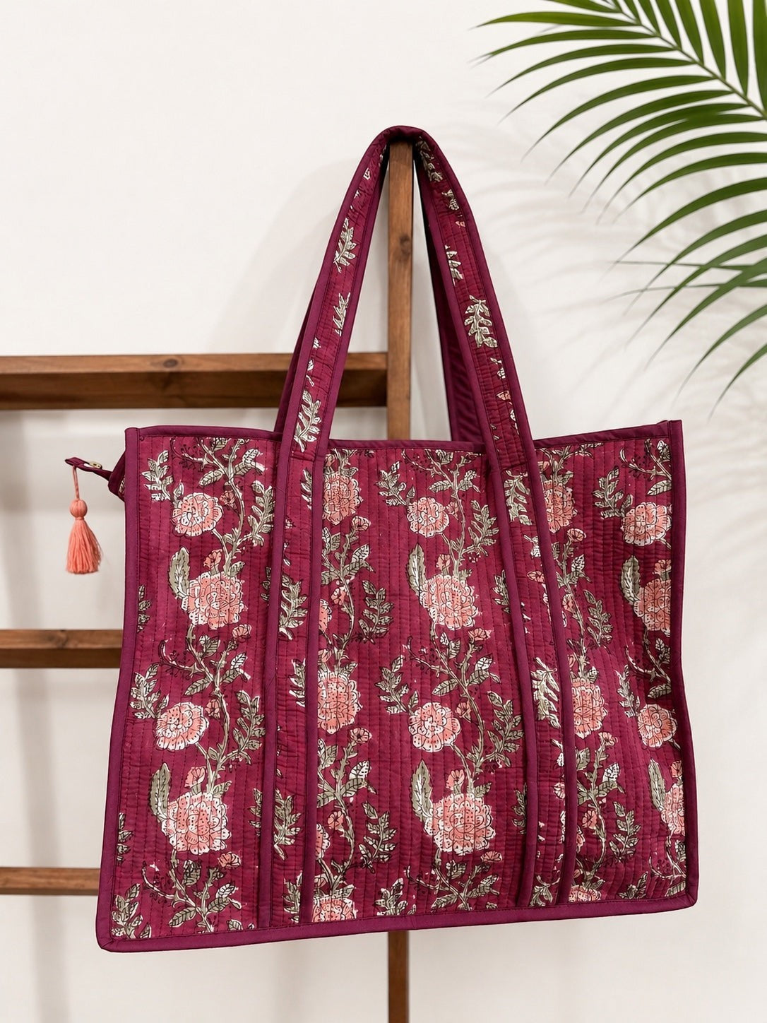 The Block & Bloom burgundy quilted tote bag with pink rose floral block print and a tassel zipper pull.