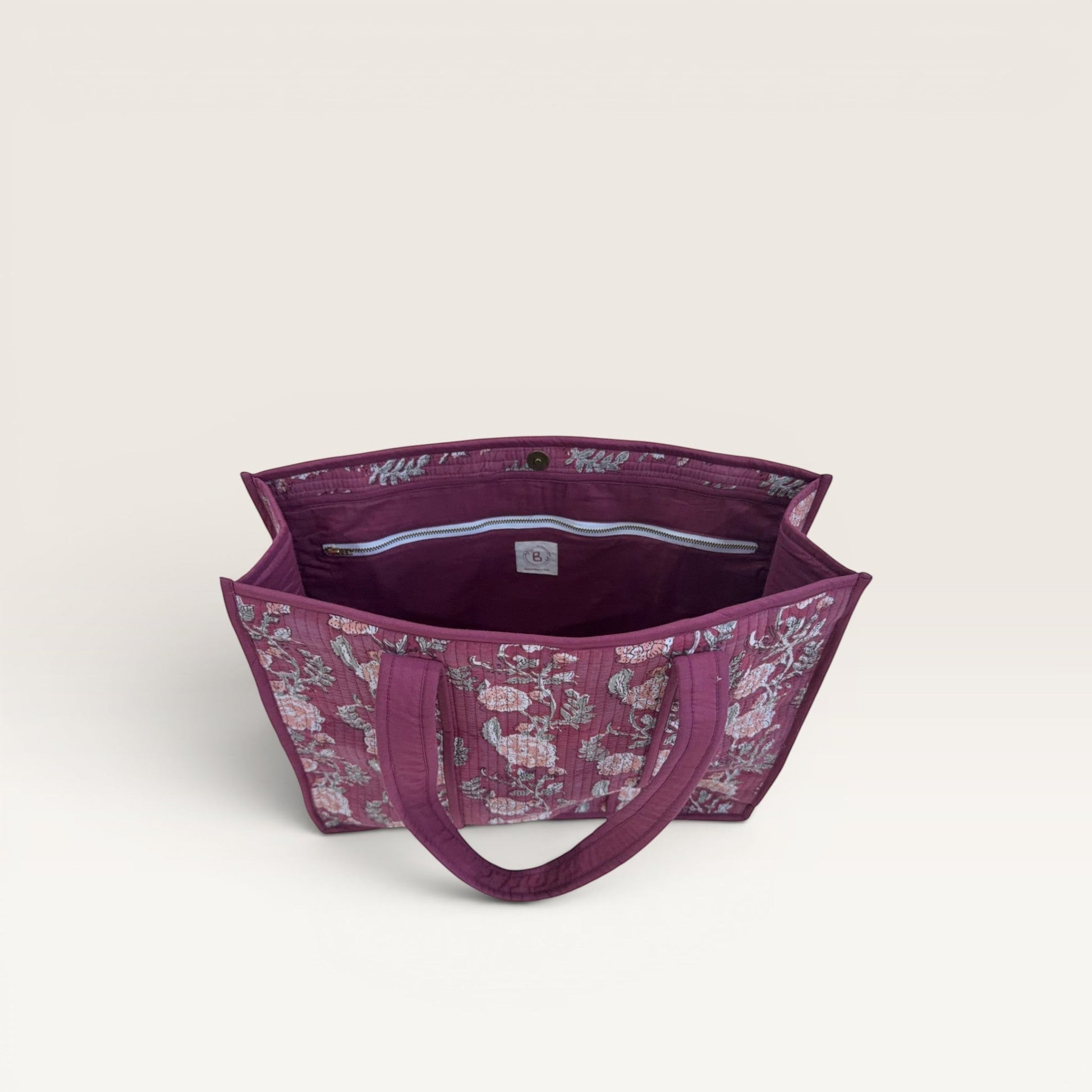 The Block & Bloom burgundy quilted tote bag with floral rose print, showing the open interior and zipper pocket.