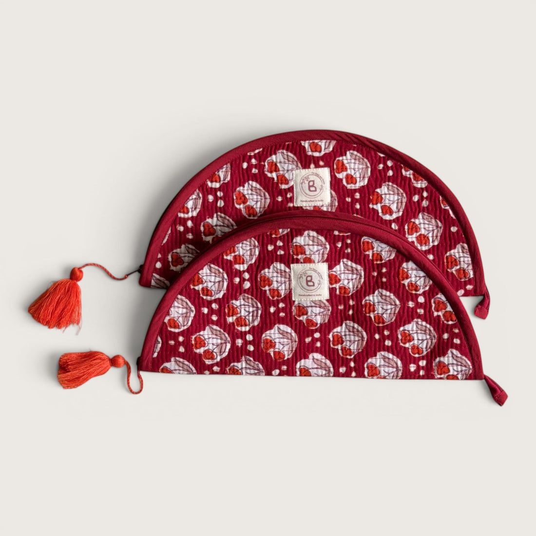 The Block & Bloom quilted makeup brush pouch in burgundy red with red tulip motifs, white dots, and tassel zippers.