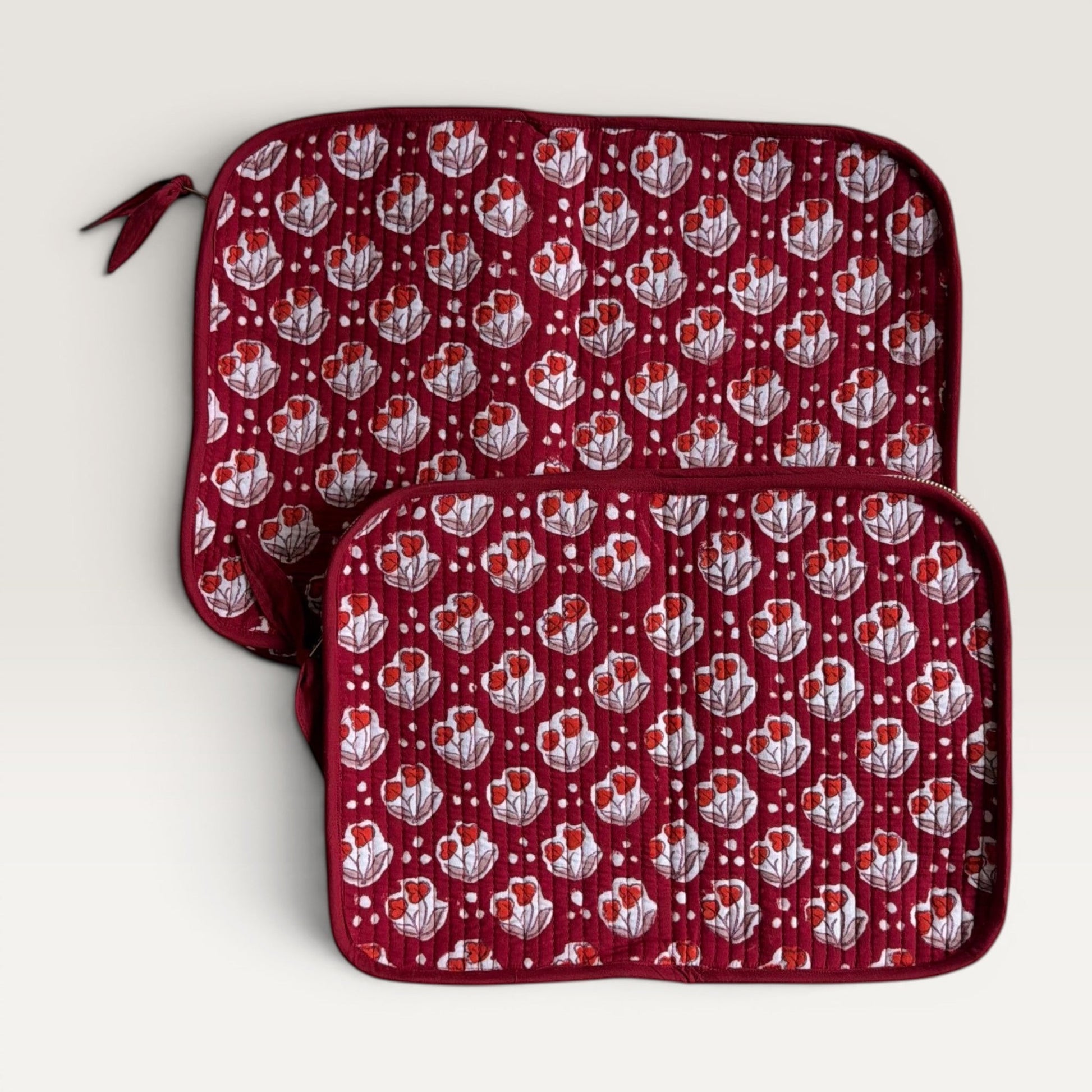 The Block & Bloom quilted laptop sleeve in burgundy red with red tulip motifs and white dot accents.