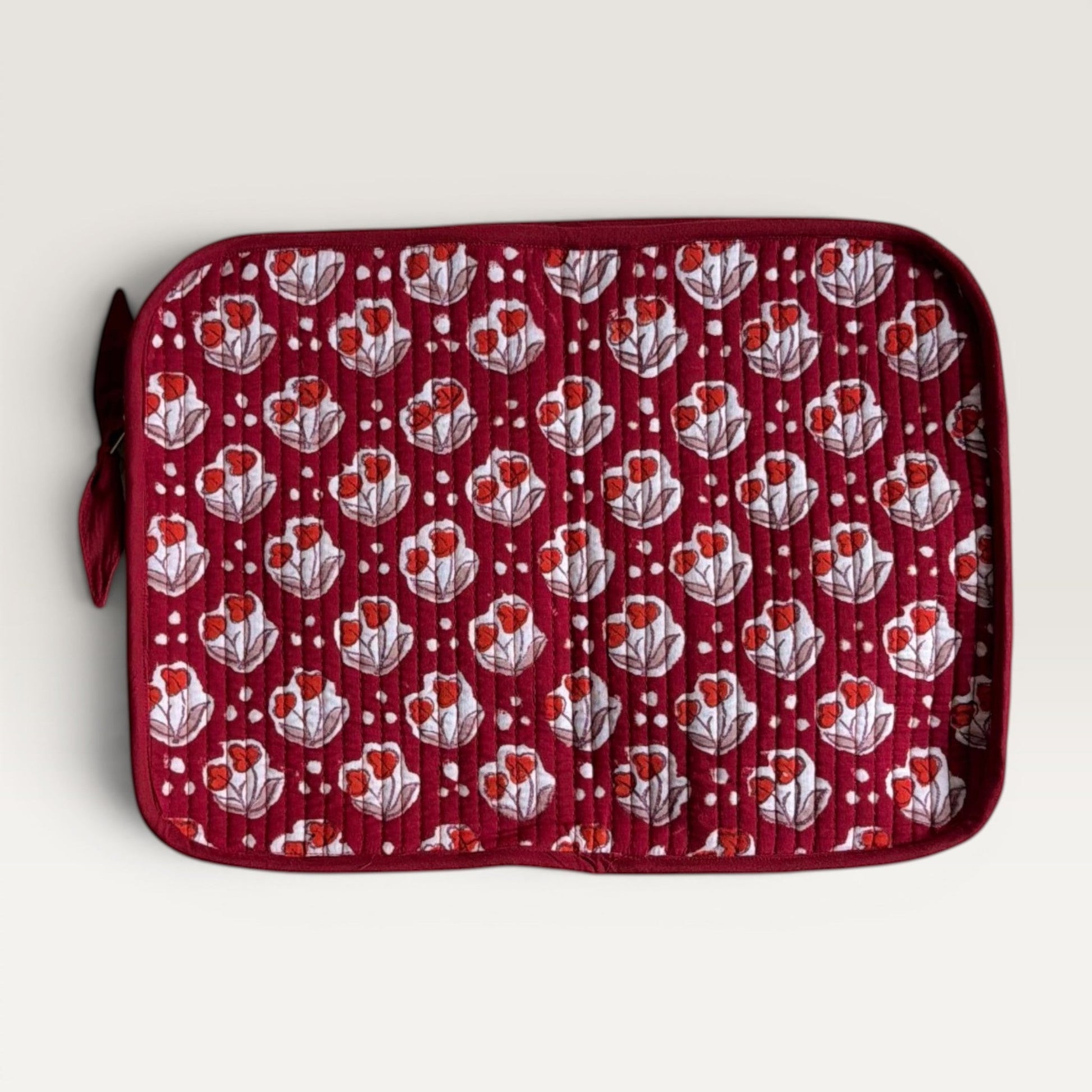 The Block & Bloom quilted laptop sleeve in burgundy red with a white tulip floral pattern and a side fabric bow.