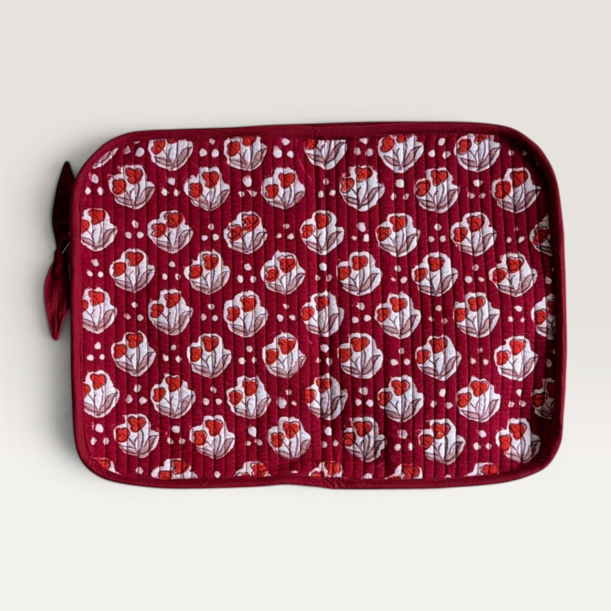 The Block & Bloom quilted laptop sleeve in burgundy red with a white tulip floral pattern and a side fabric bow.