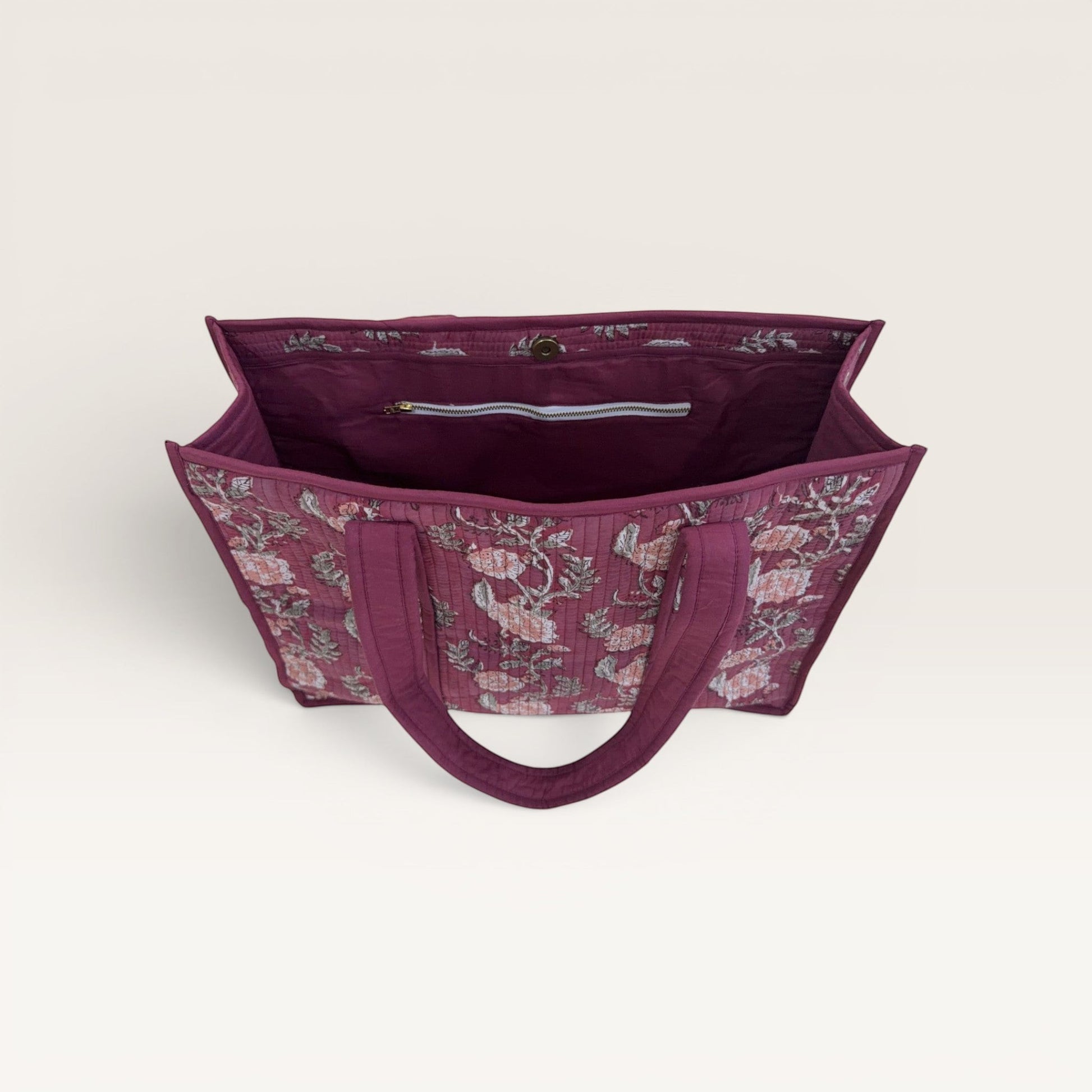 The Block & Bloom burgundy quilted tote bag with pink rose floral print, featuring an open top and interior pockets.