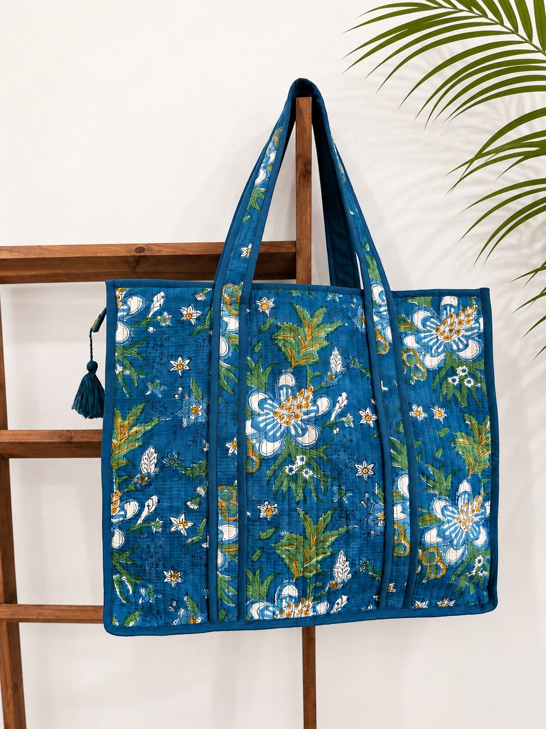 The Block & Bloom Gardenia Bloom quilted tote bag in cobalt blue with white floral block print and sturdy handles.