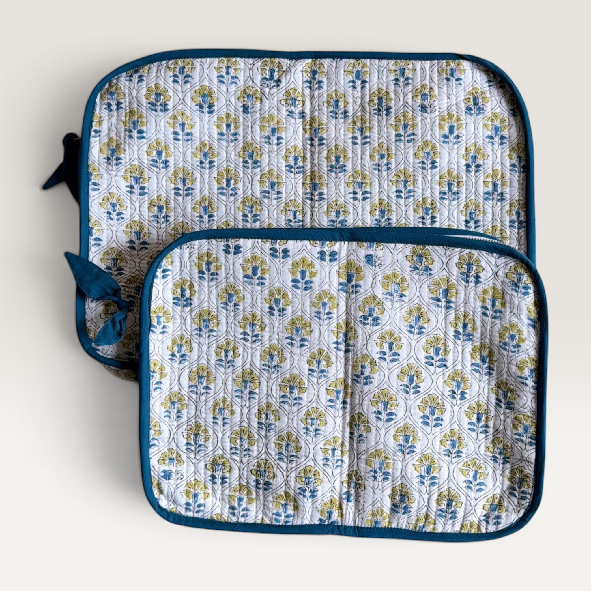The Block & Bloom quilted laptop sleeve with blue and yellow cosmos floral print on white fabric and blue trim.