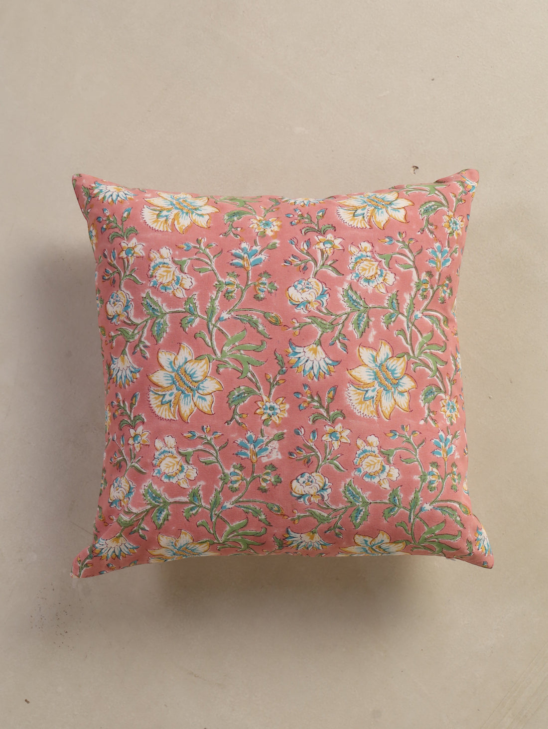 The Block & Bloom hand block printed cotton cushion cover in dusty rose with white, yellow, and teal floral patterns.