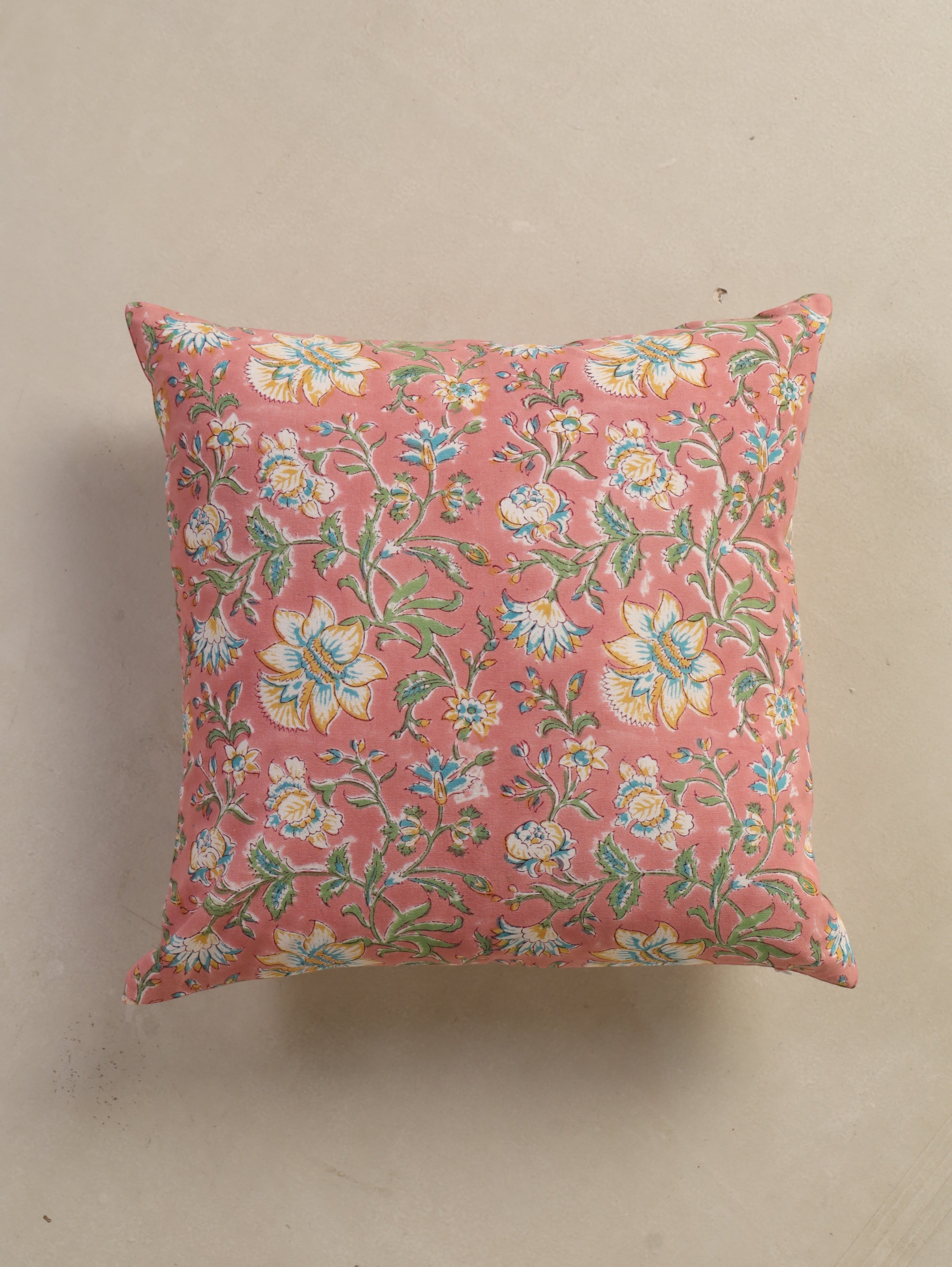 The Block & Bloom hand block printed cotton cushion cover in dusty rose with white, yellow, and teal floral patterns.