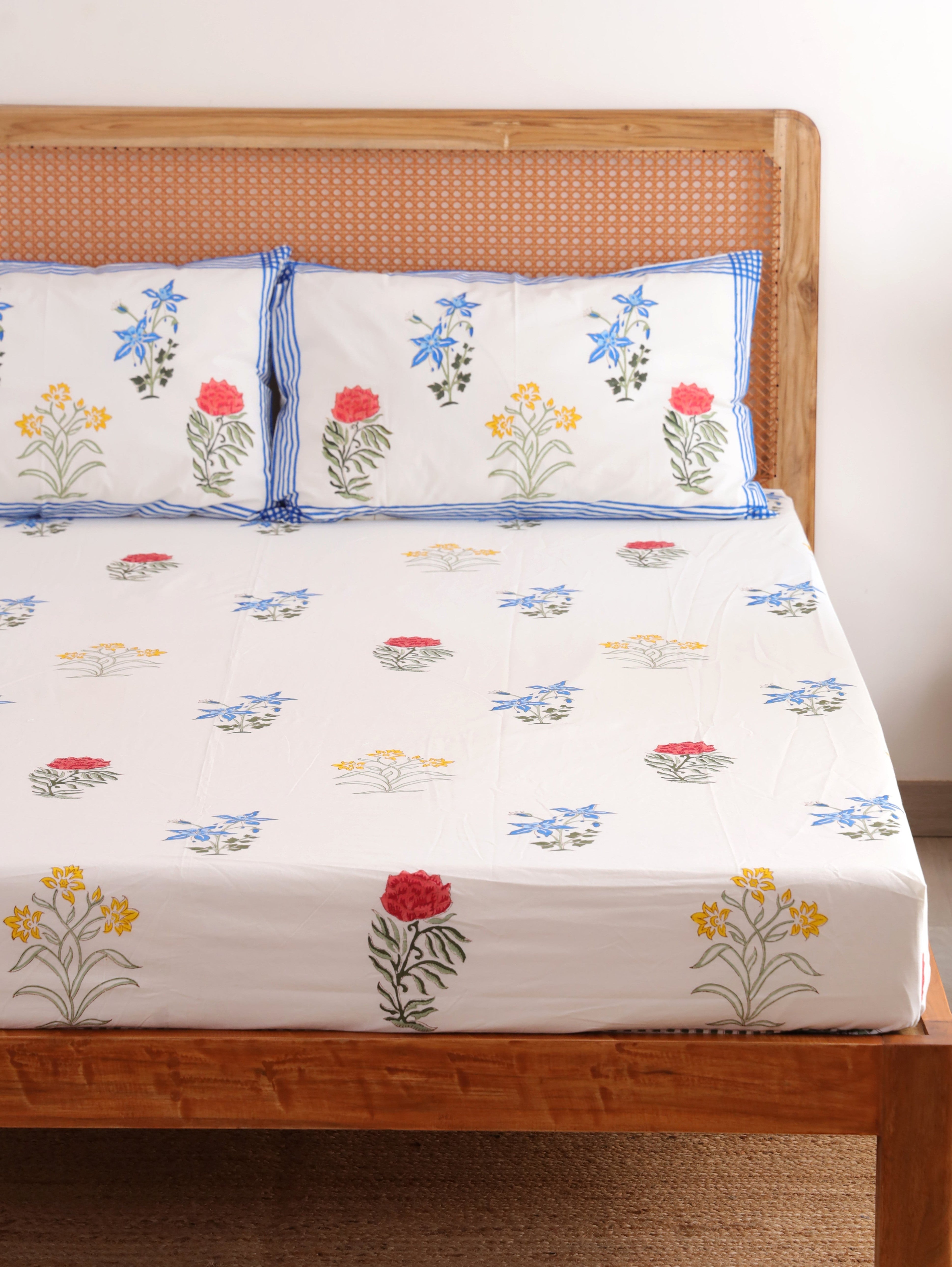 The Block & Bloom Wildflower Bagh cotton fitted sheet and pillowcases with blue, pink, and yellow floral block prints.