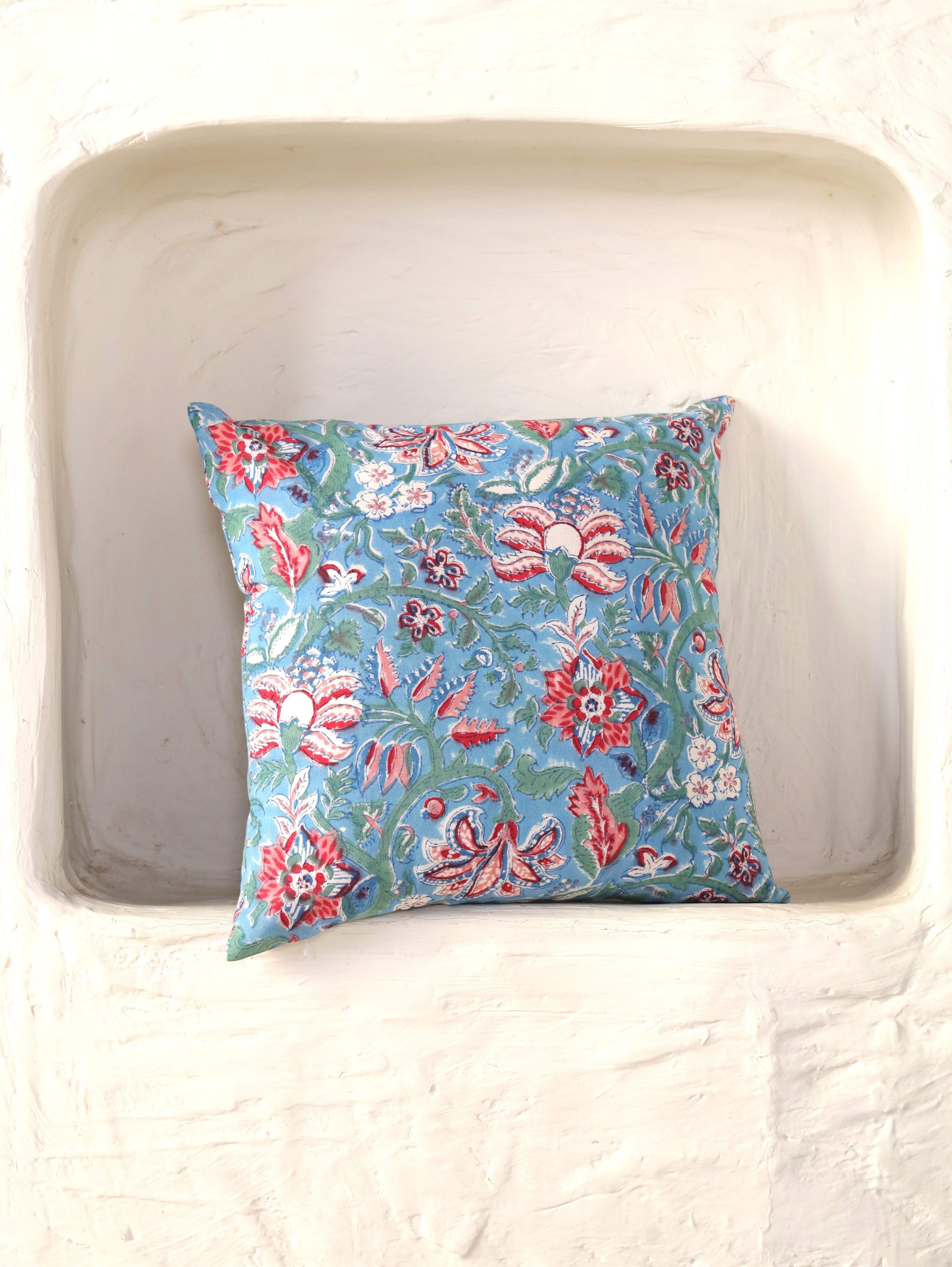 The Block & Bloom hand block printed cotton cushion cover featuring red and rose floral patterns on cornflower blue.