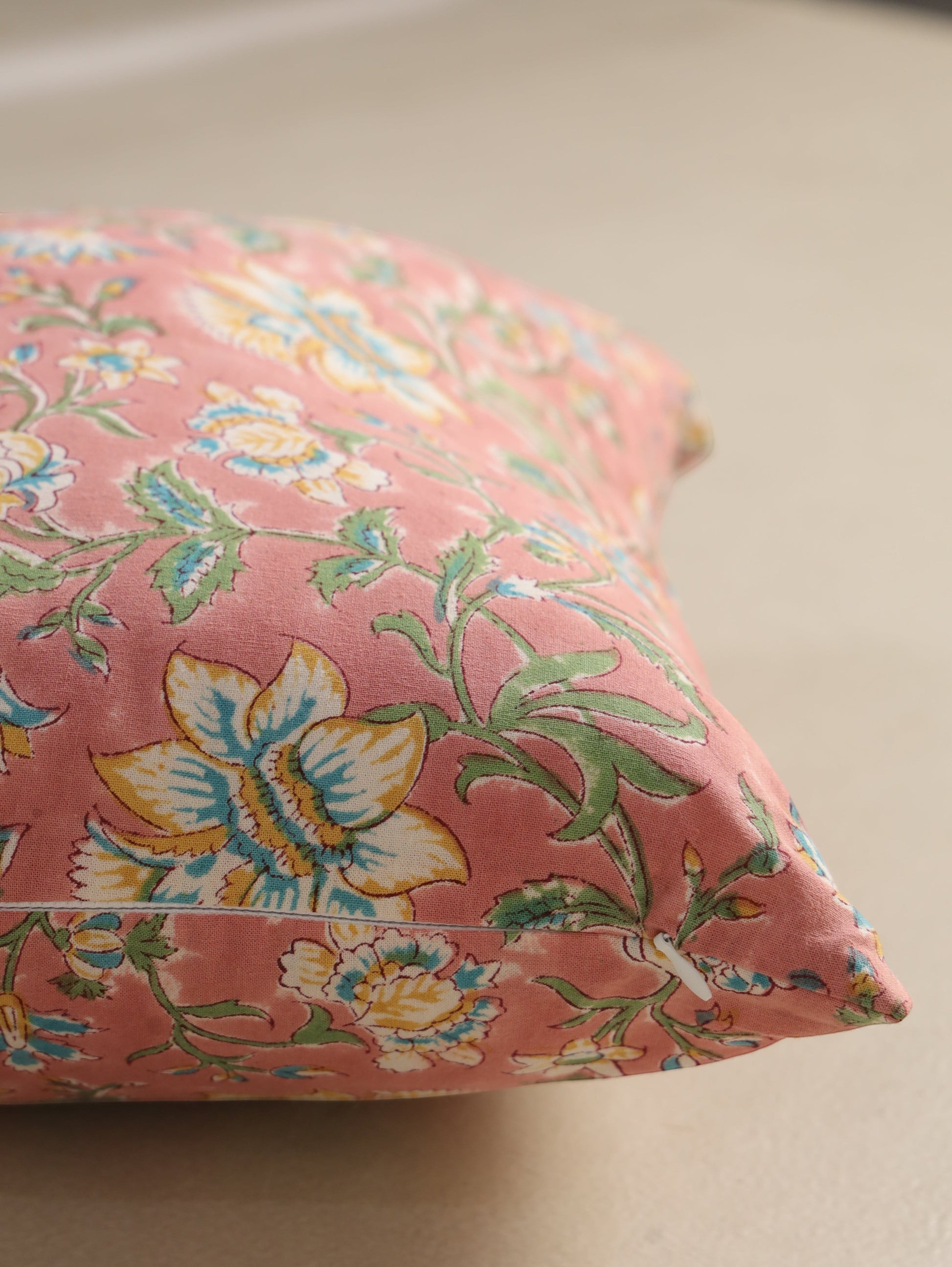 The Block & Bloom hand block printed cotton cushion cover in dusty rose with floral patterns in yellow and teal.