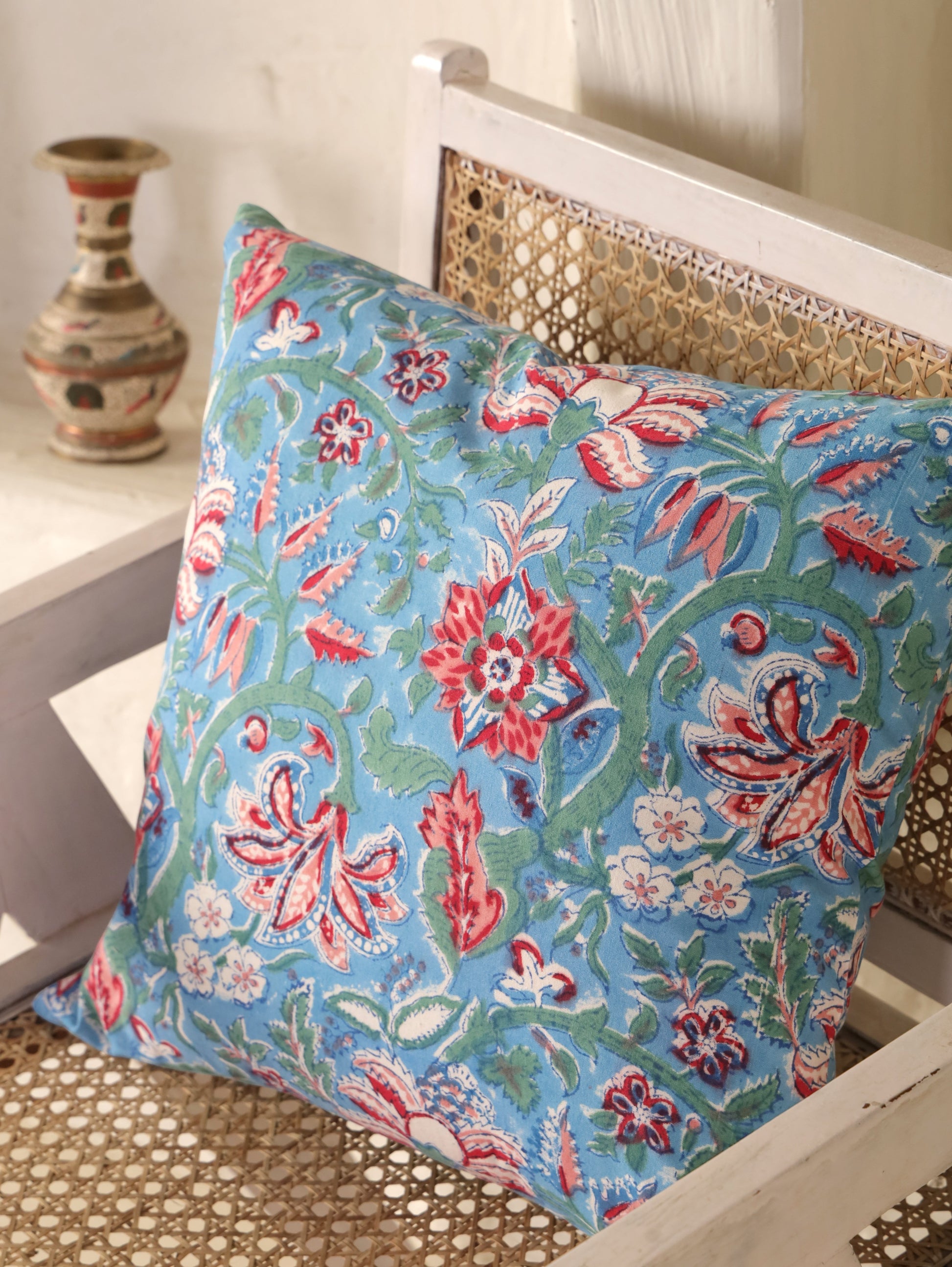 The Block & Bloom hand block printed cotton cushion cover featuring red and rose floral patterns on cornflower blue.