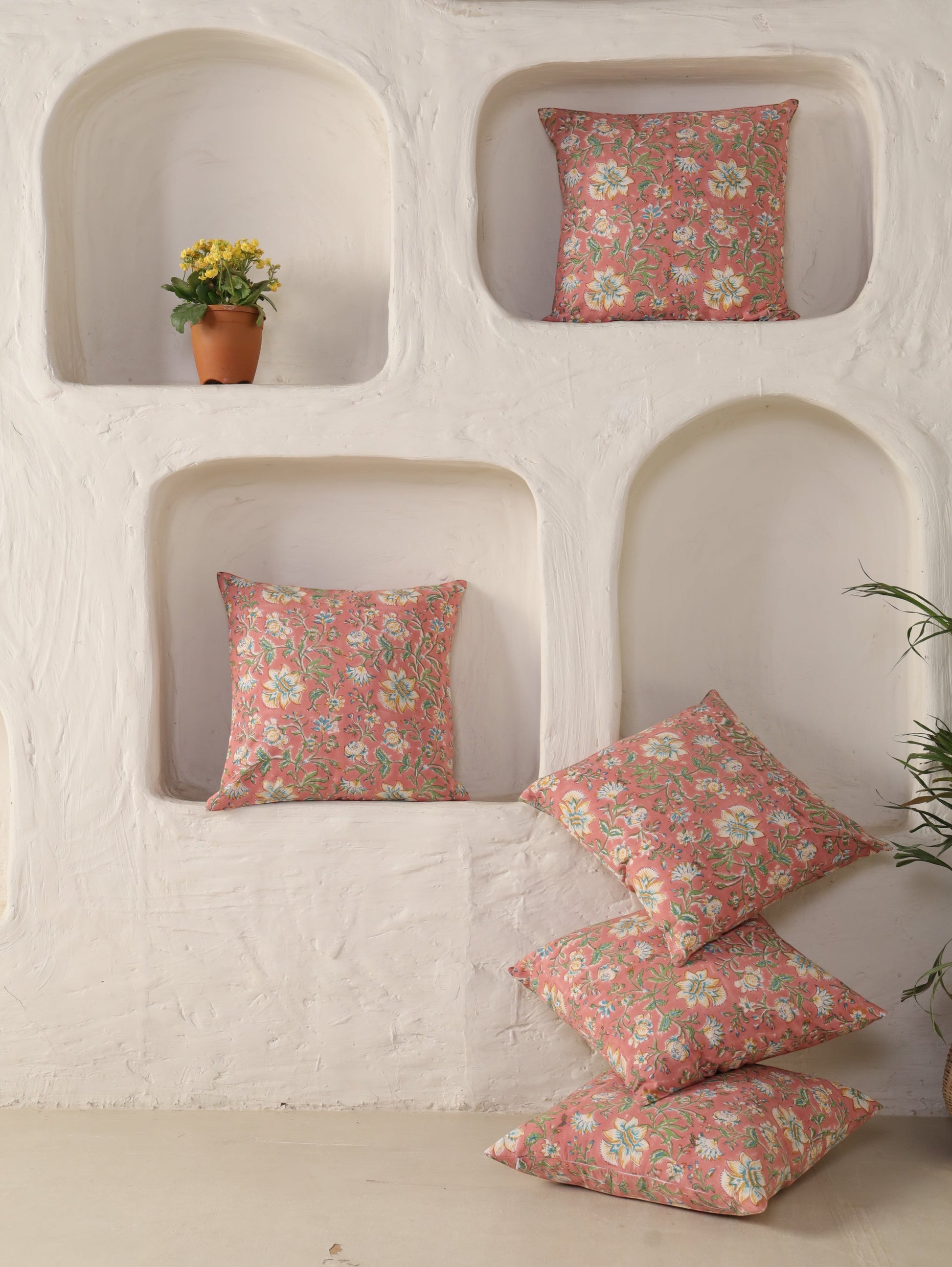 The Block & Bloom hand block printed cotton cushion covers in dusty rose with floral patterns in white and yellow.