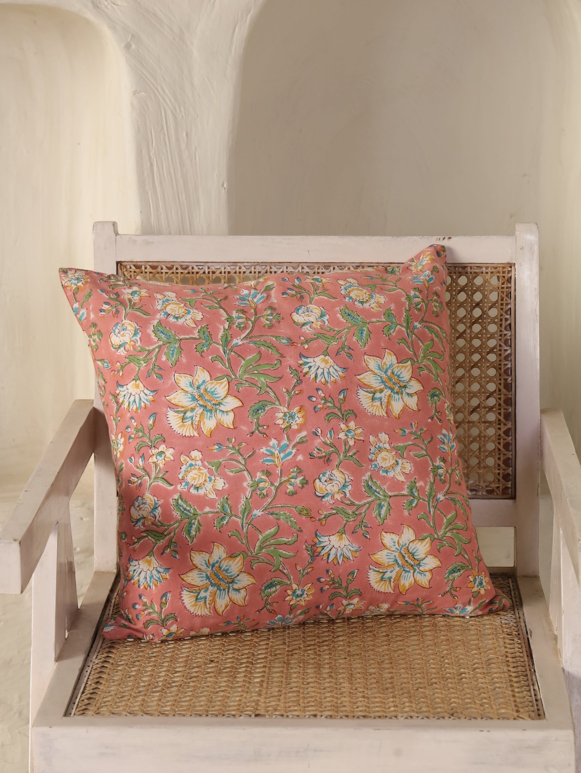 The Block & Bloom hand block printed cotton cushion cover in dusty rose with white, yellow, and teal floral patterns.