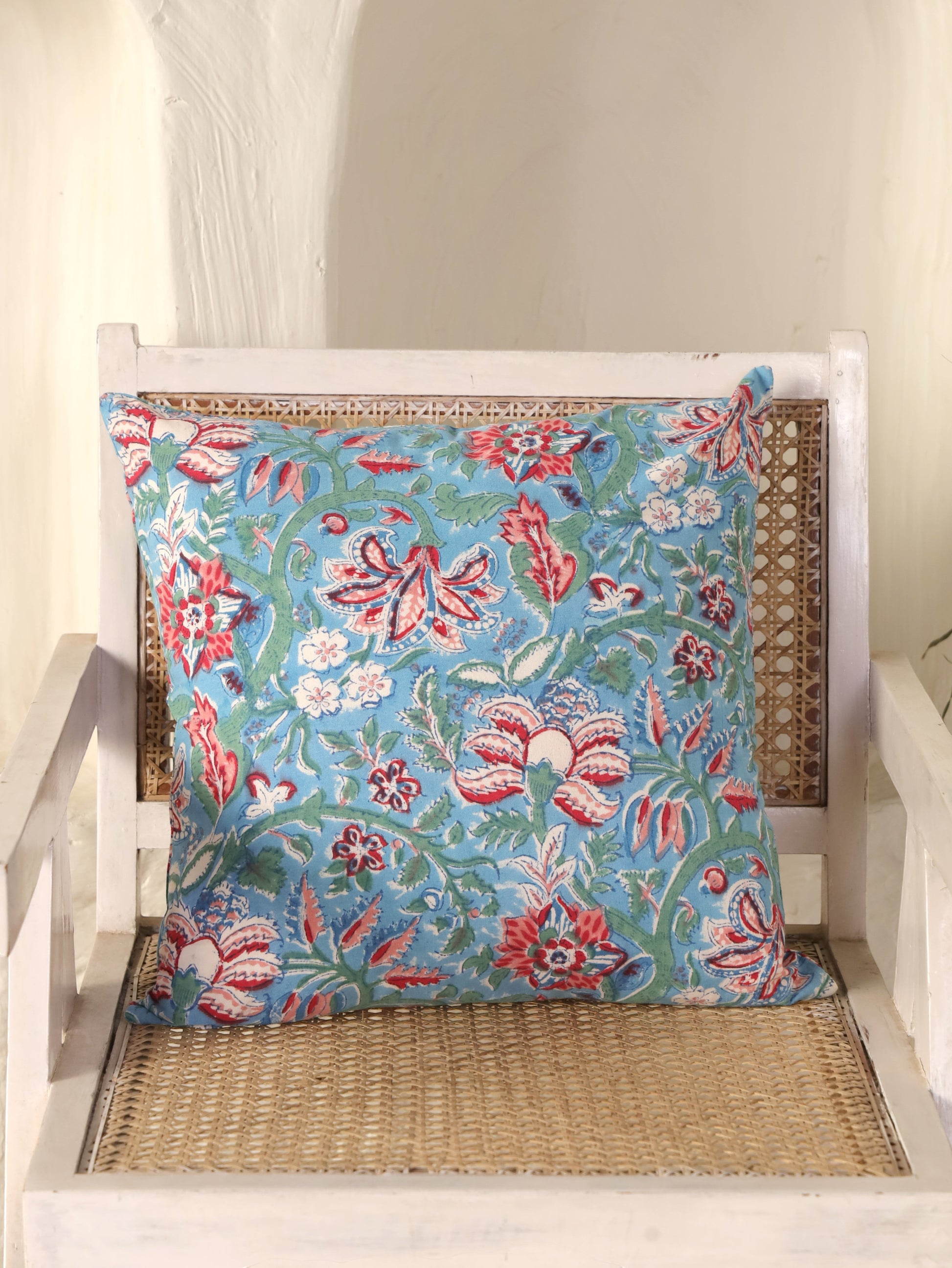 The Block & Bloom hand block printed cotton cushion cover featuring red and rose floral patterns on cornflower blue.