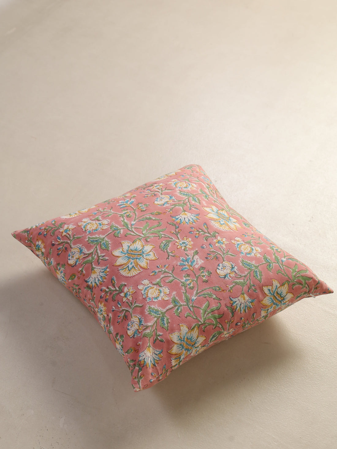 The Block & Bloom hand block printed cotton cushion cover in dusty rose with white, yellow, and teal floral patterns.