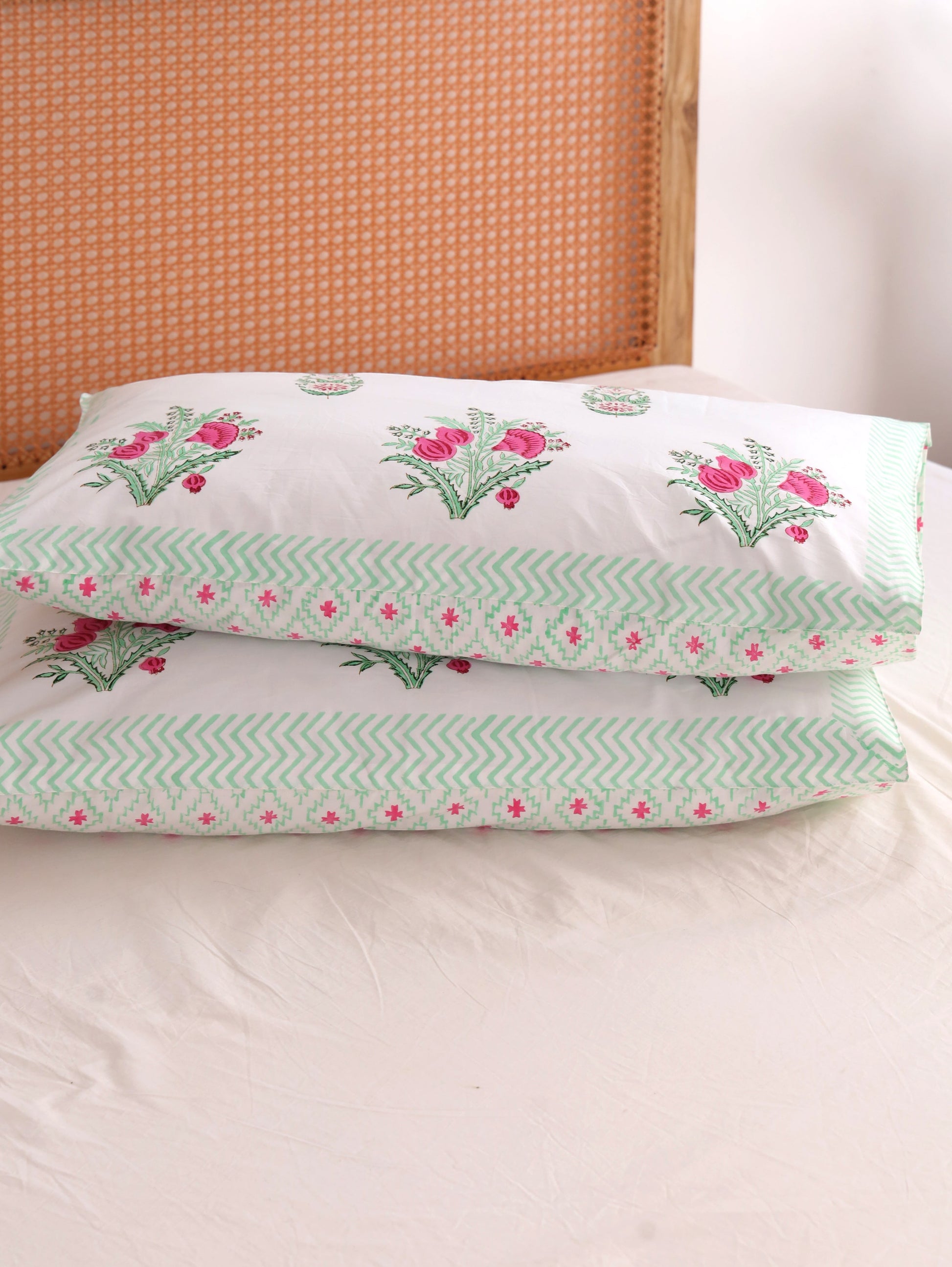 The Block & Bloom hand block printed cotton pillowcases with pink pomegranate floral print and green chevron border.