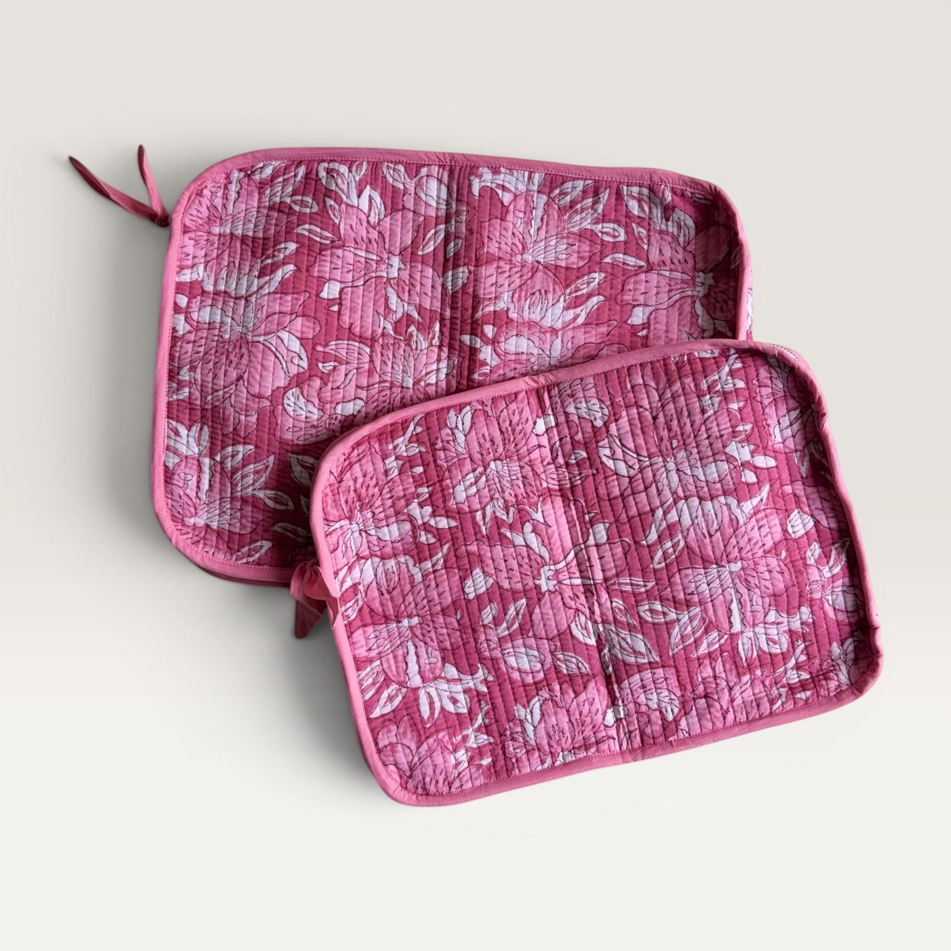 The Block & Bloom quilted laptop sleeve featuring a deep pink and white floral lily print with a fabric bow zipper pull.