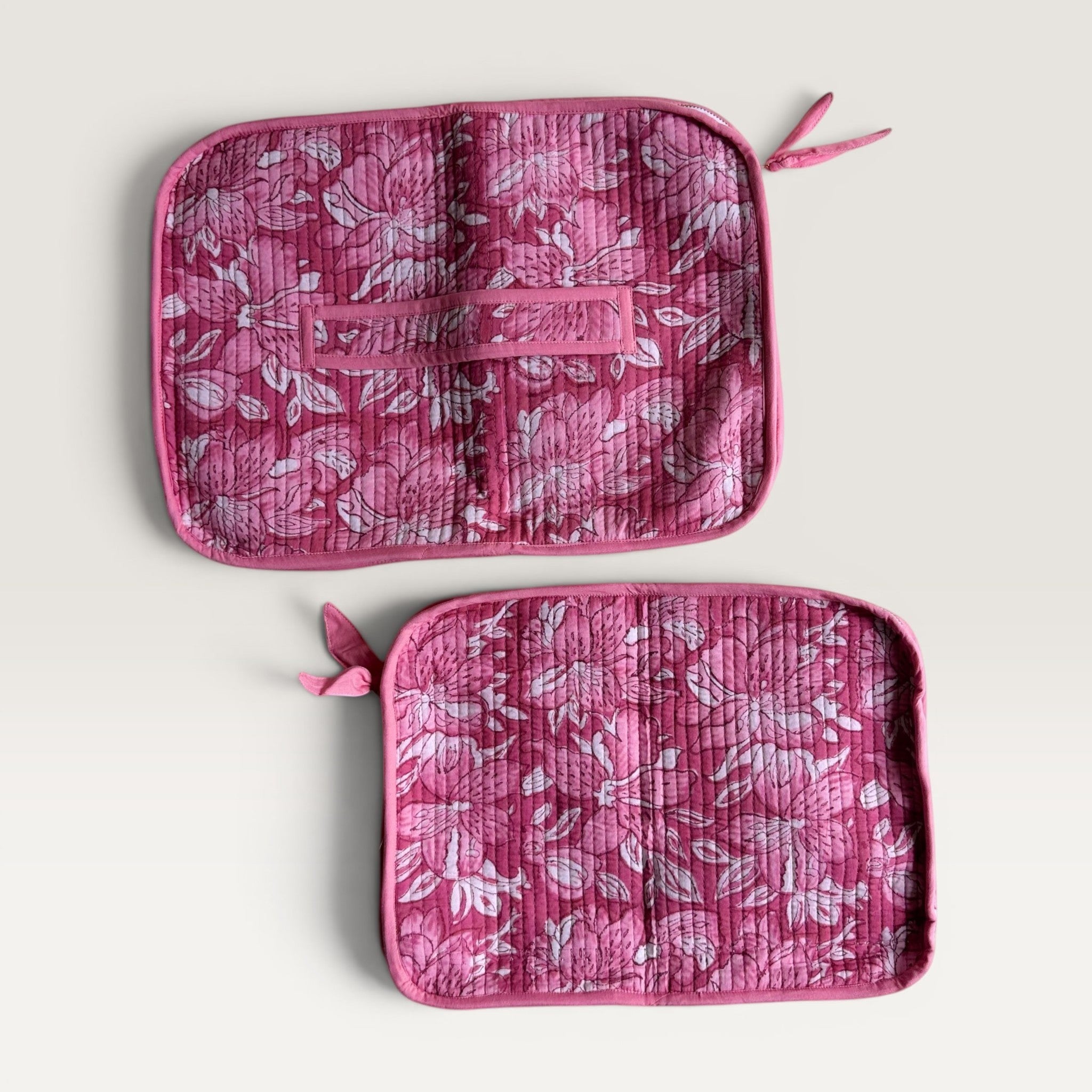 The Block & Bloom quilted laptop sleeve featuring a deep pink and white floral lily print with a back carry strap.