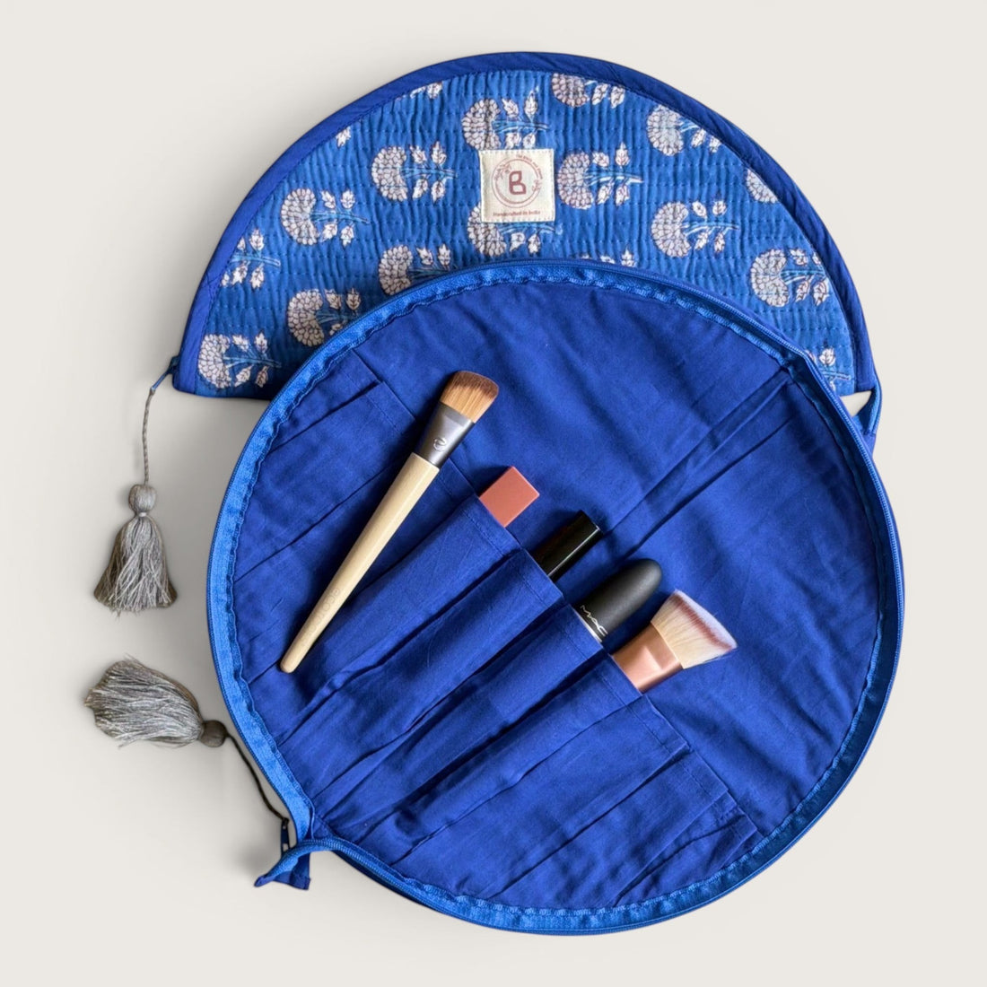 The Block & Bloom indigo blue quilted cotton makeup brush pouch featuring a white marigold floral print and tassels.