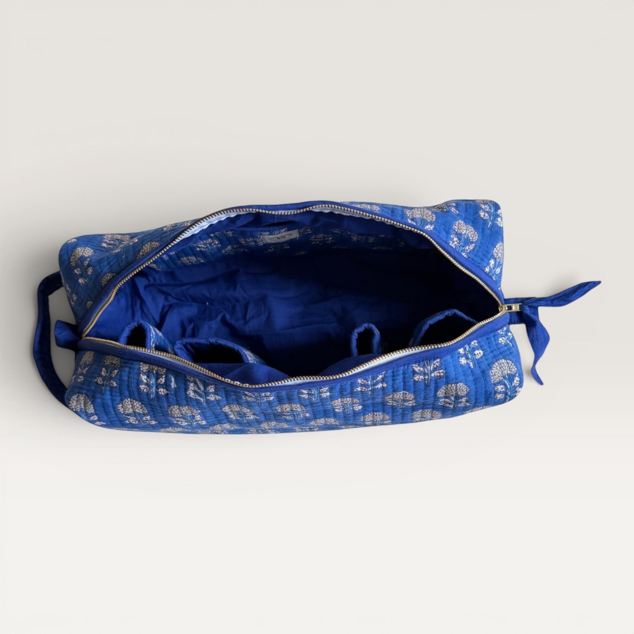The Block & Bloom Indigo Marigold quilted hair tool organizer bag with white floral print and internal storage slots.