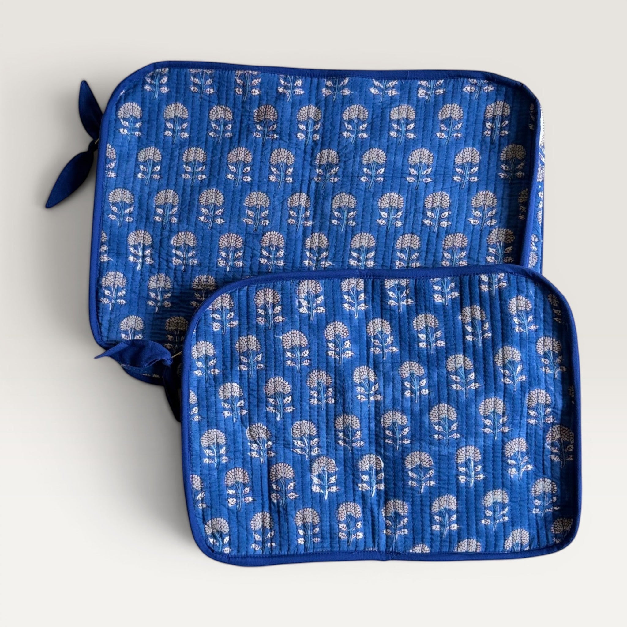 The Block & Bloom indigo blue quilted cotton laptop sleeve with hand block-printed white marigold floral patterns.