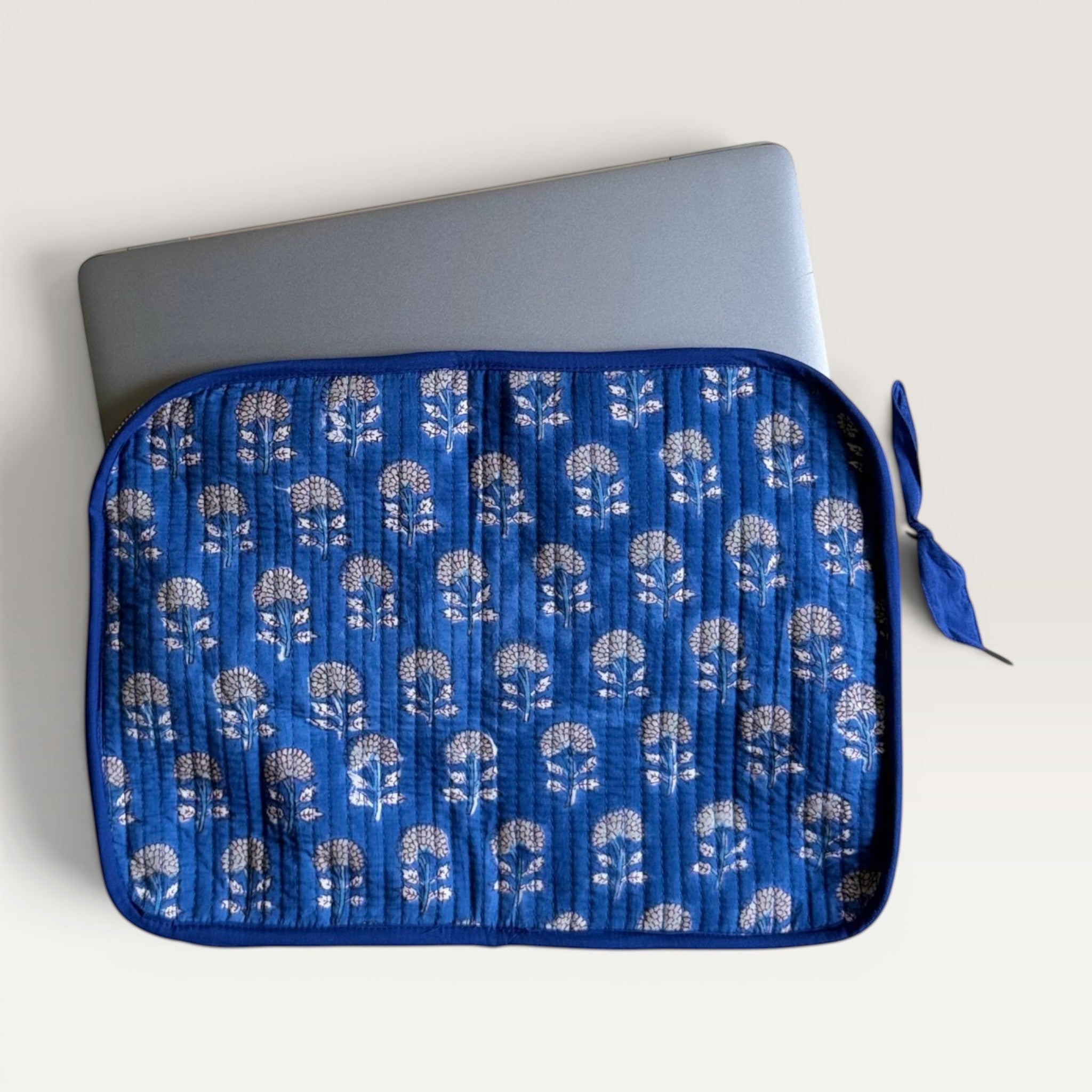 The Block & Bloom indigo blue quilted cotton laptop sleeve with hand block-printed marigold floral patterns.