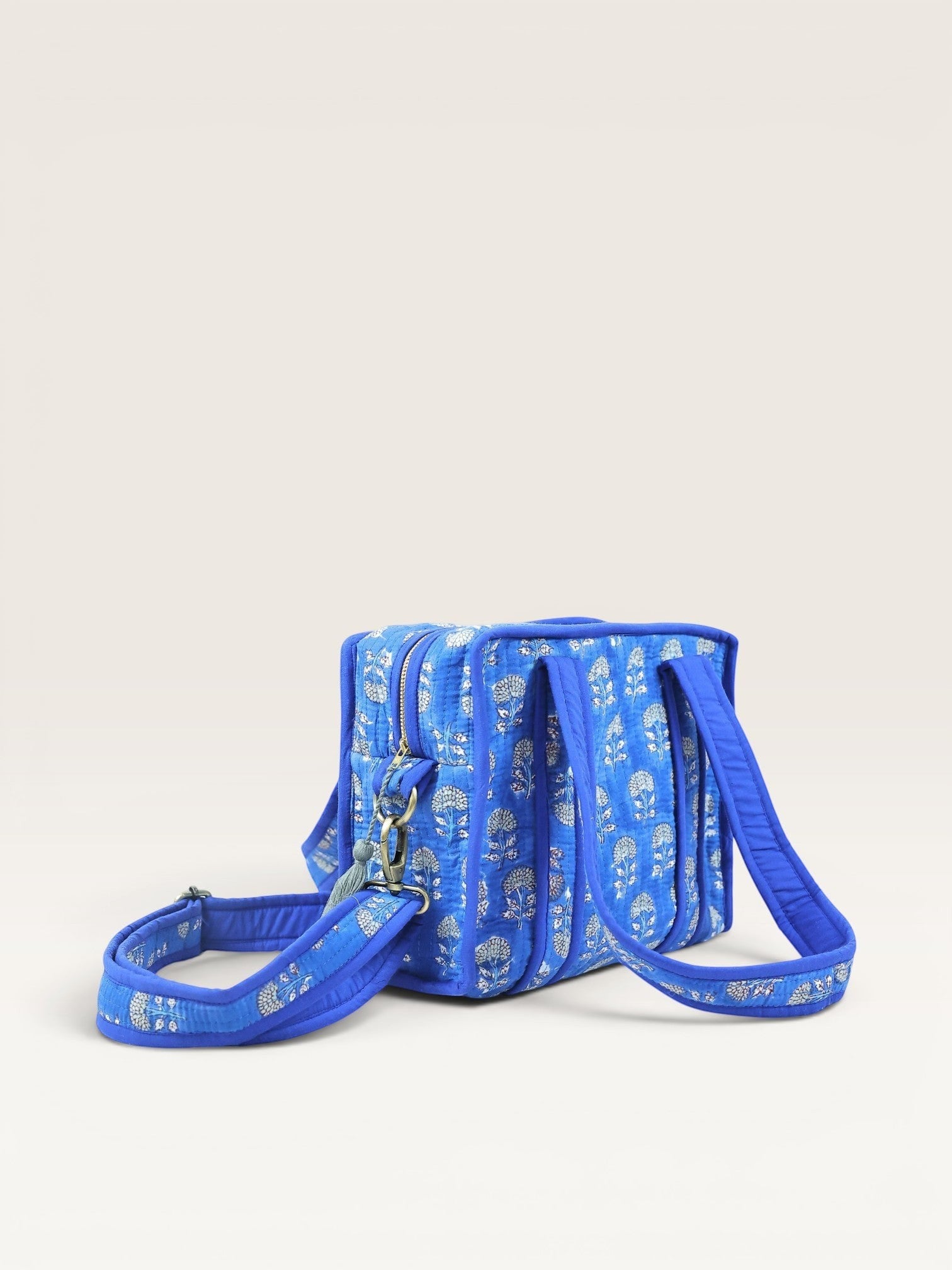 The Block & Bloom indigo blue quilted mini tote bag with white marigold block print, shoulder handles, and strap.
