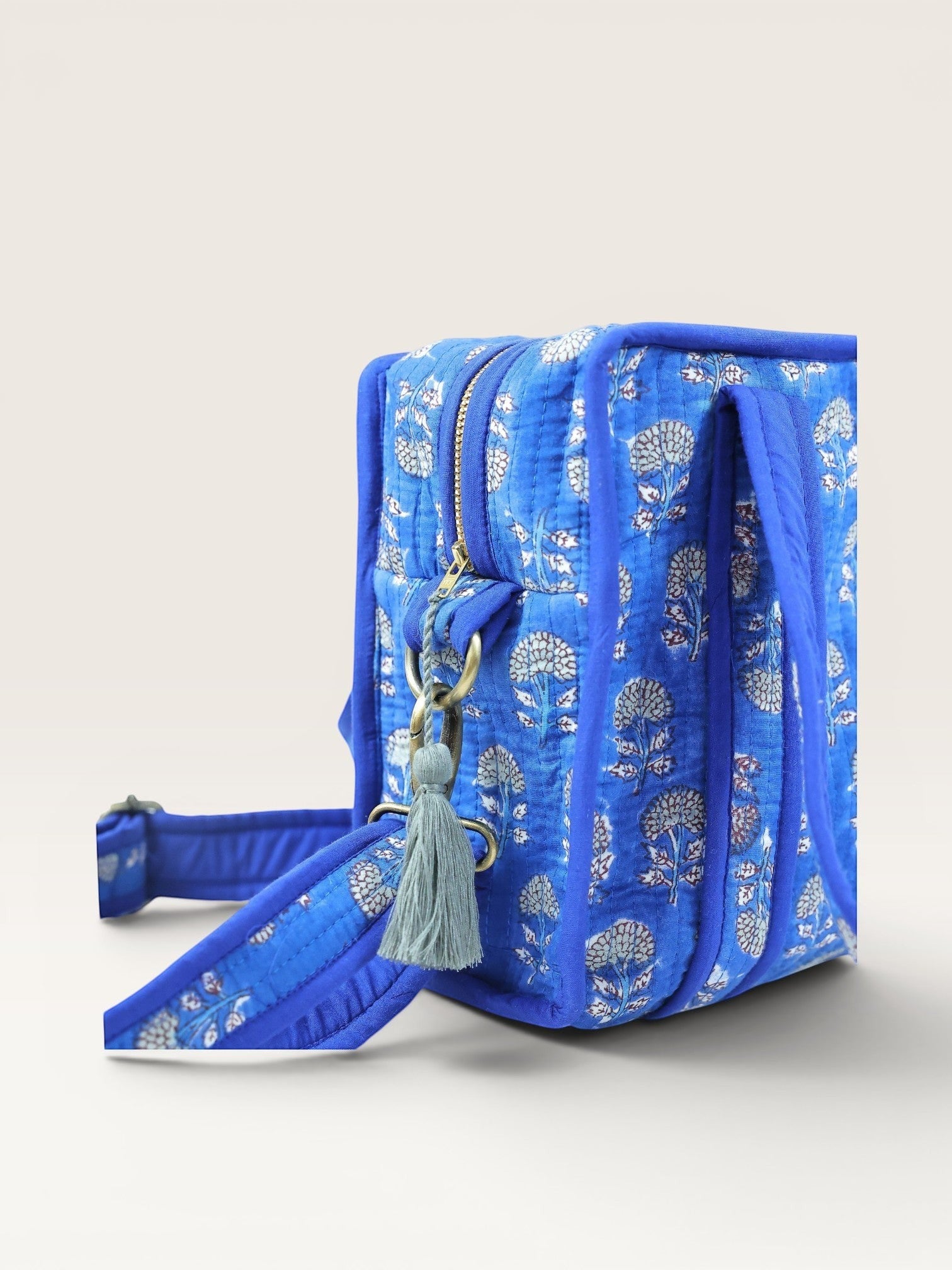 The Block & Bloom indigo blue quilted mini tote with white marigold block print, brass hardware, and crossbody strap.