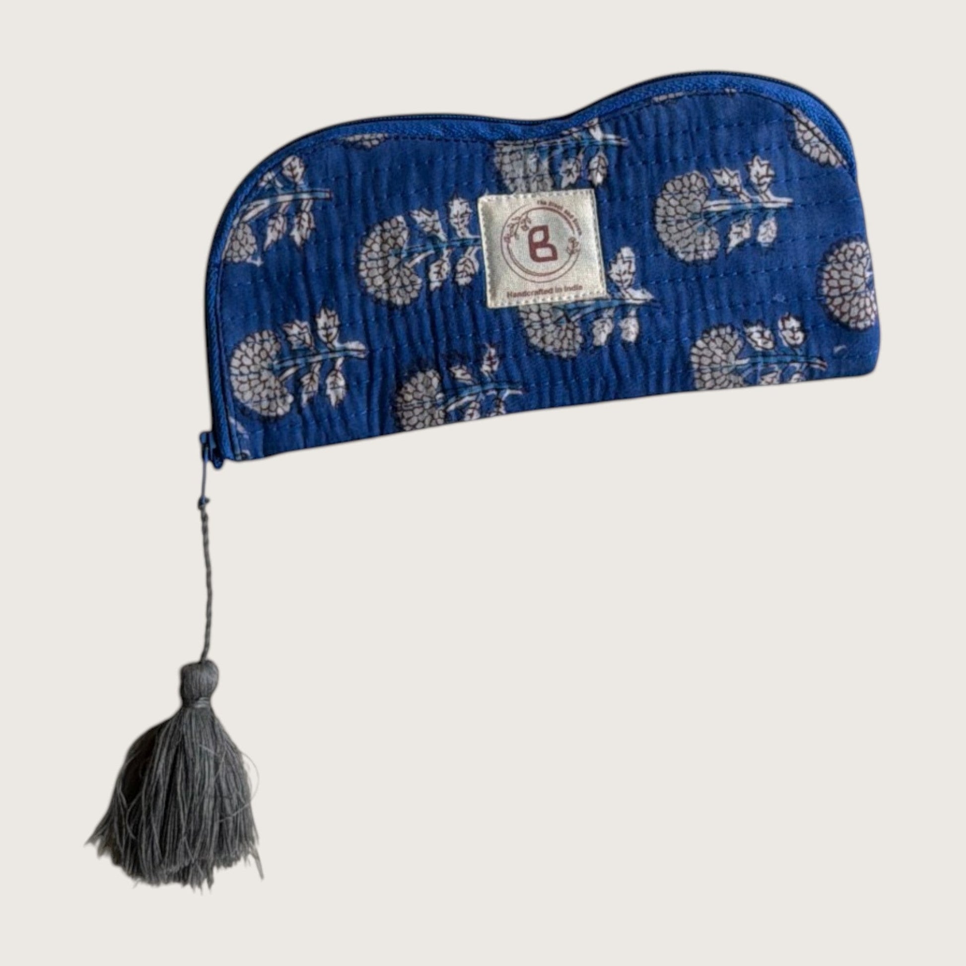 The Block & Bloom indigo blue quilted cotton sunglasses pouch with a marigold floral print and grey tassel zipper pull.