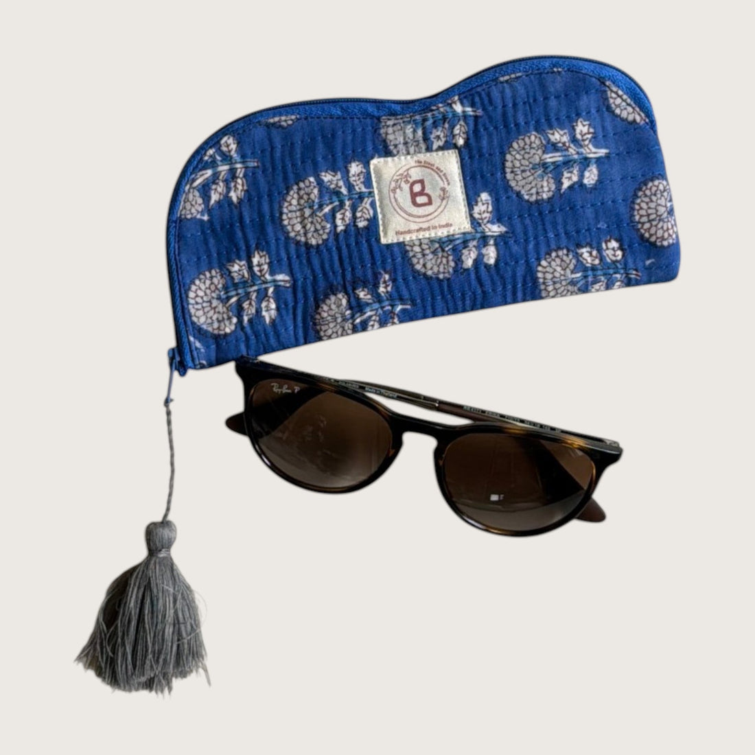 The Block & Bloom indigo blue quilted cotton sunglasses pouch with marigold floral print and grey tassel detail.