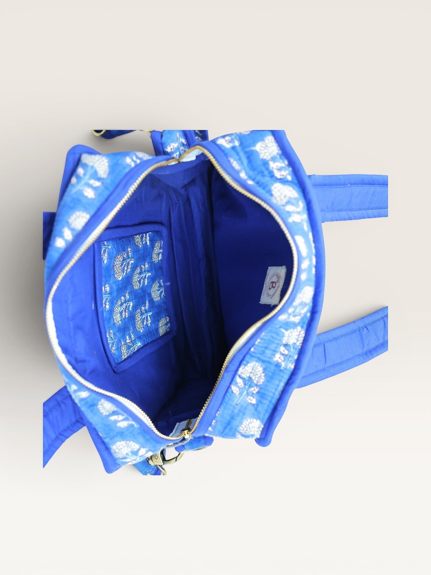 The Block & Bloom indigo blue quilted mini tote bag with white marigold block print, open top with inner pocket.