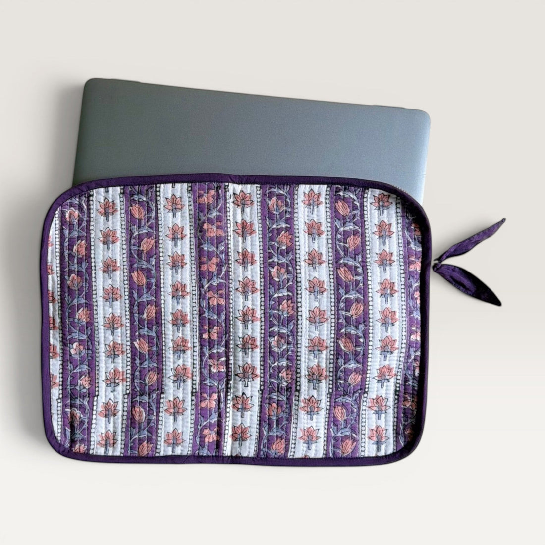 The Block & Bloom quilted laptop sleeve in lavender and ivory with hand block-printed floral vine patterns and a bow.