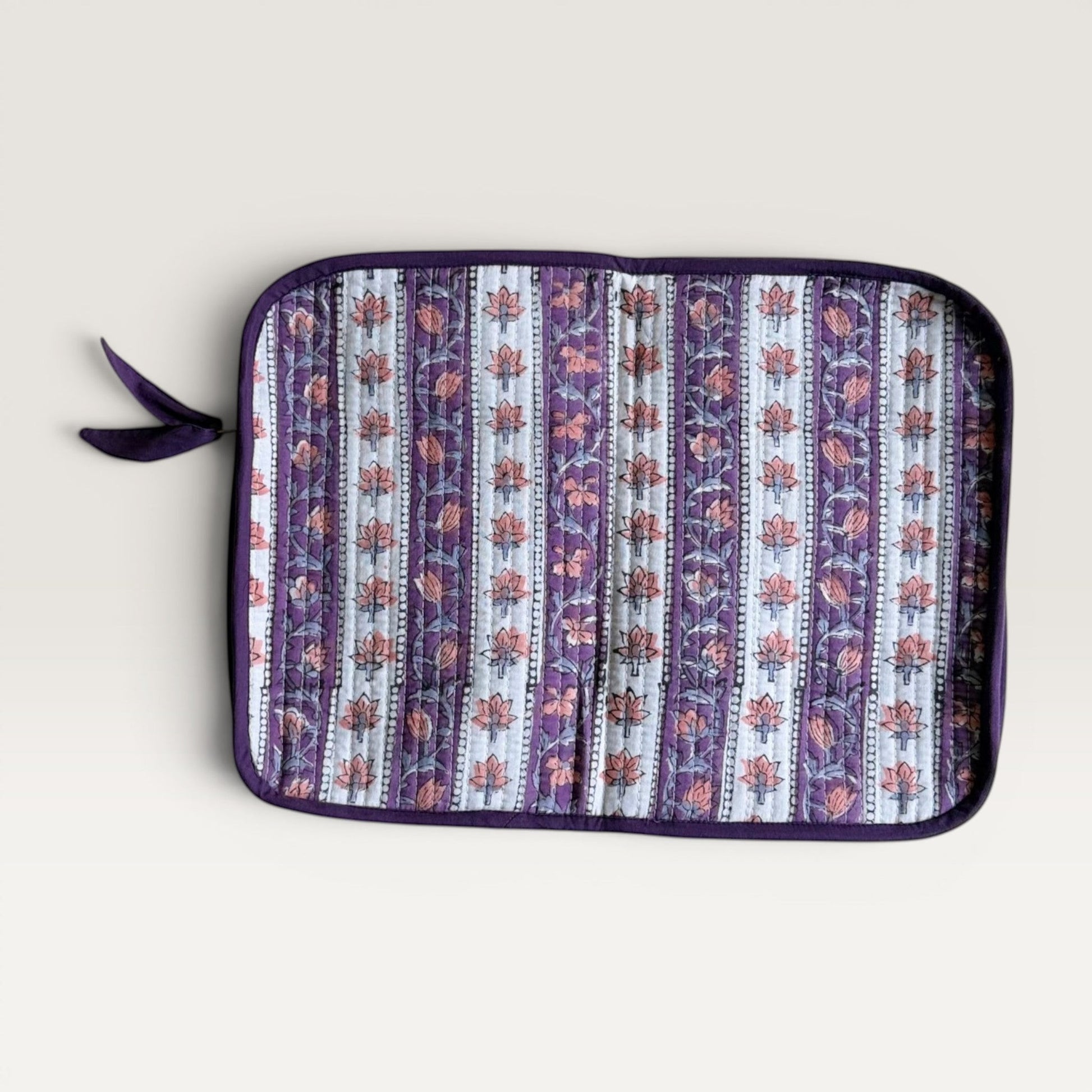 The Block & Bloom quilted laptop sleeve with lavender and ivory floral vine block print and a fabric bow zipper pull.