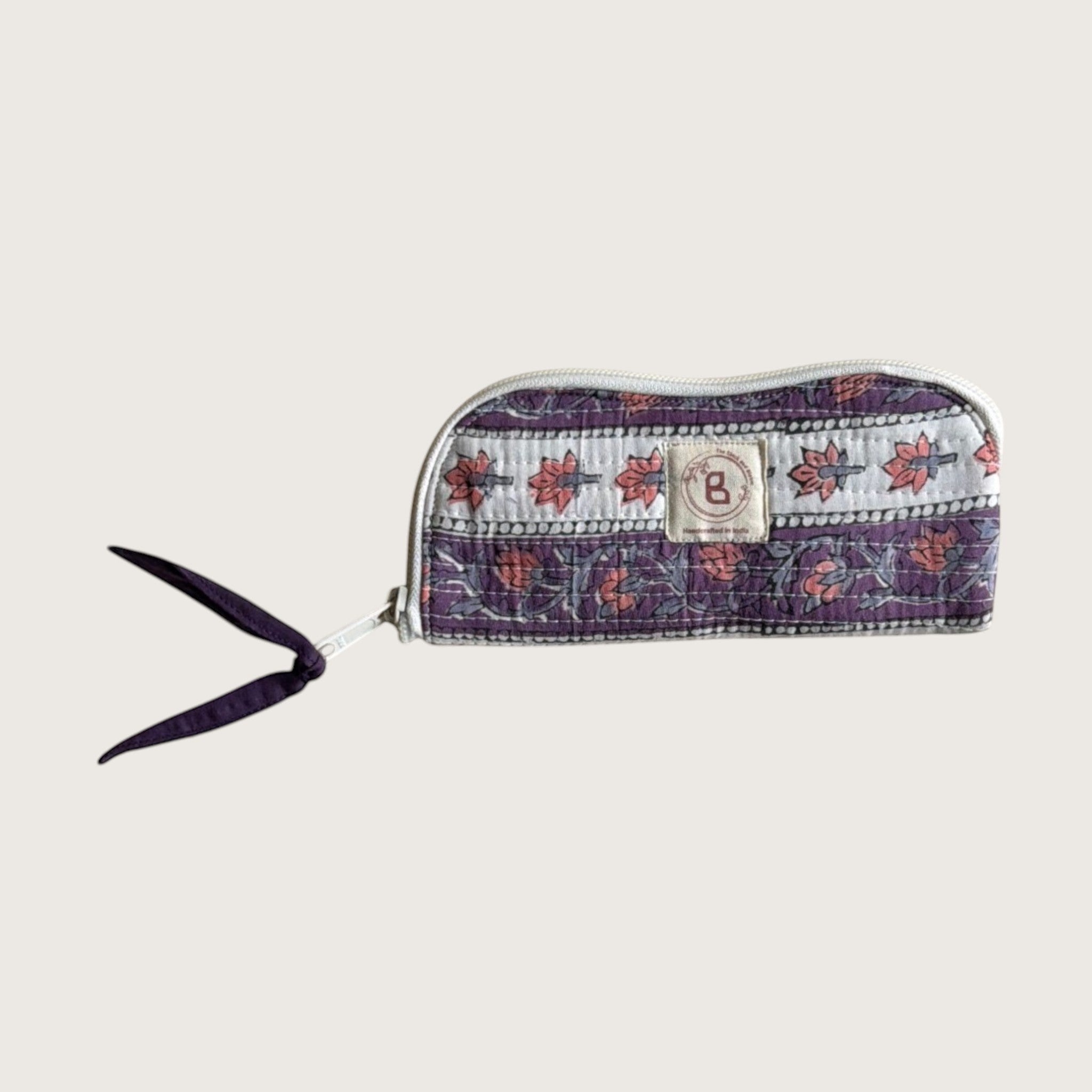 The Block & Bloom quilted cotton sunglasses pouch in lavender with white floral vines and a fabric bow zipper pull.