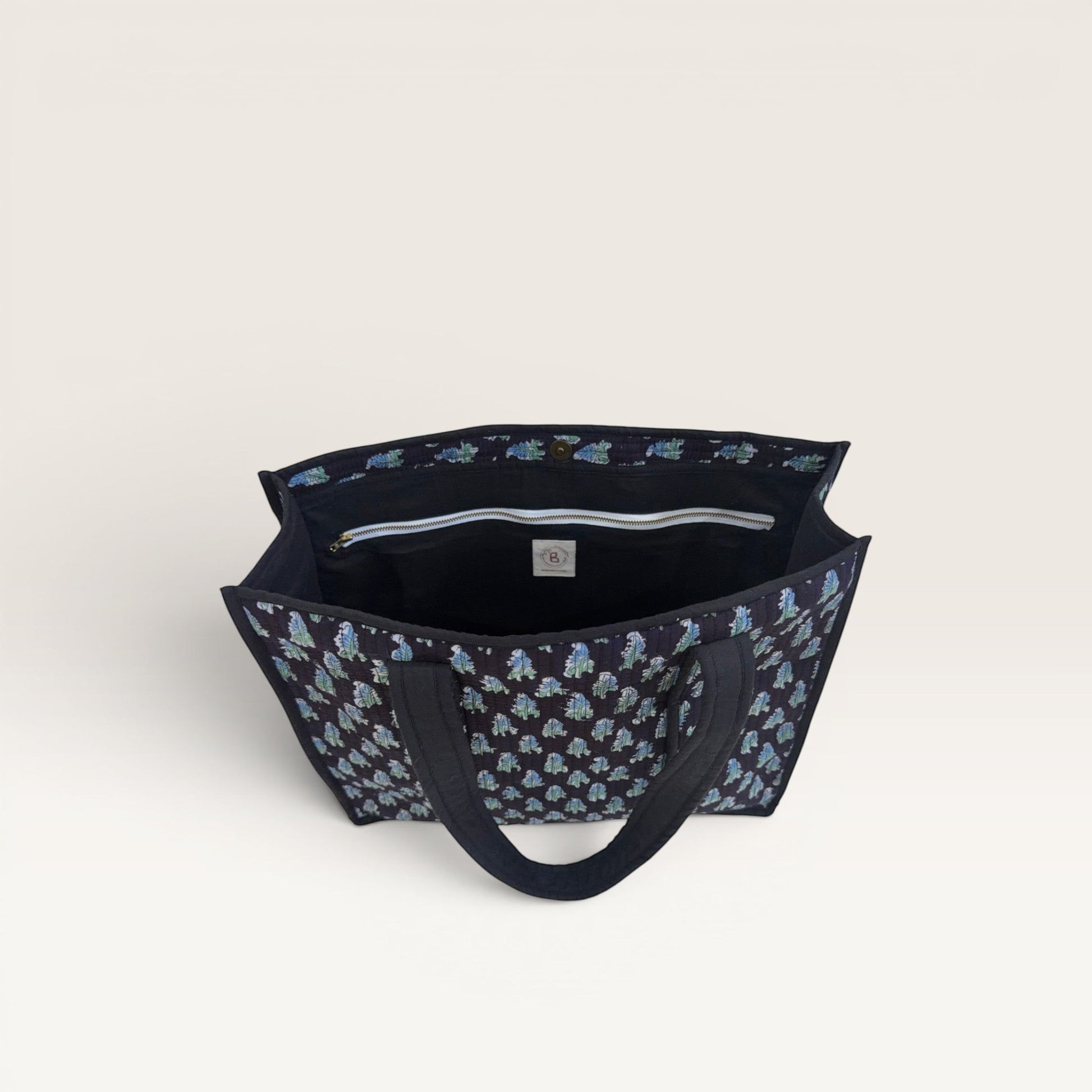 The Block & Bloom Midnight Fern quilted tote bag with blue and green leaf print, showing the interior laptop pocket.