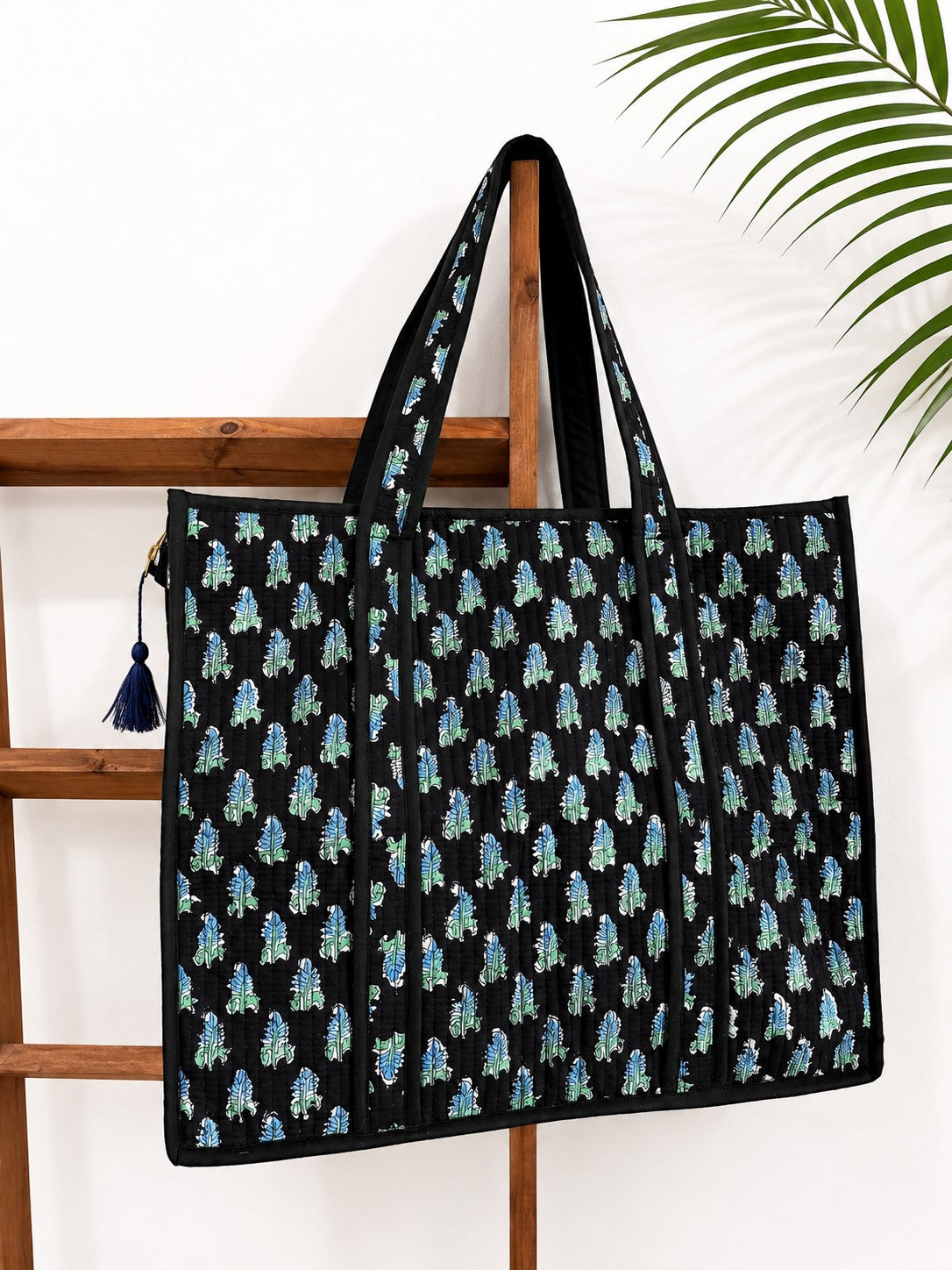 The Block & Bloom Midnight Fern quilted tote bag in black with blue and sage green leaf print and structured base.