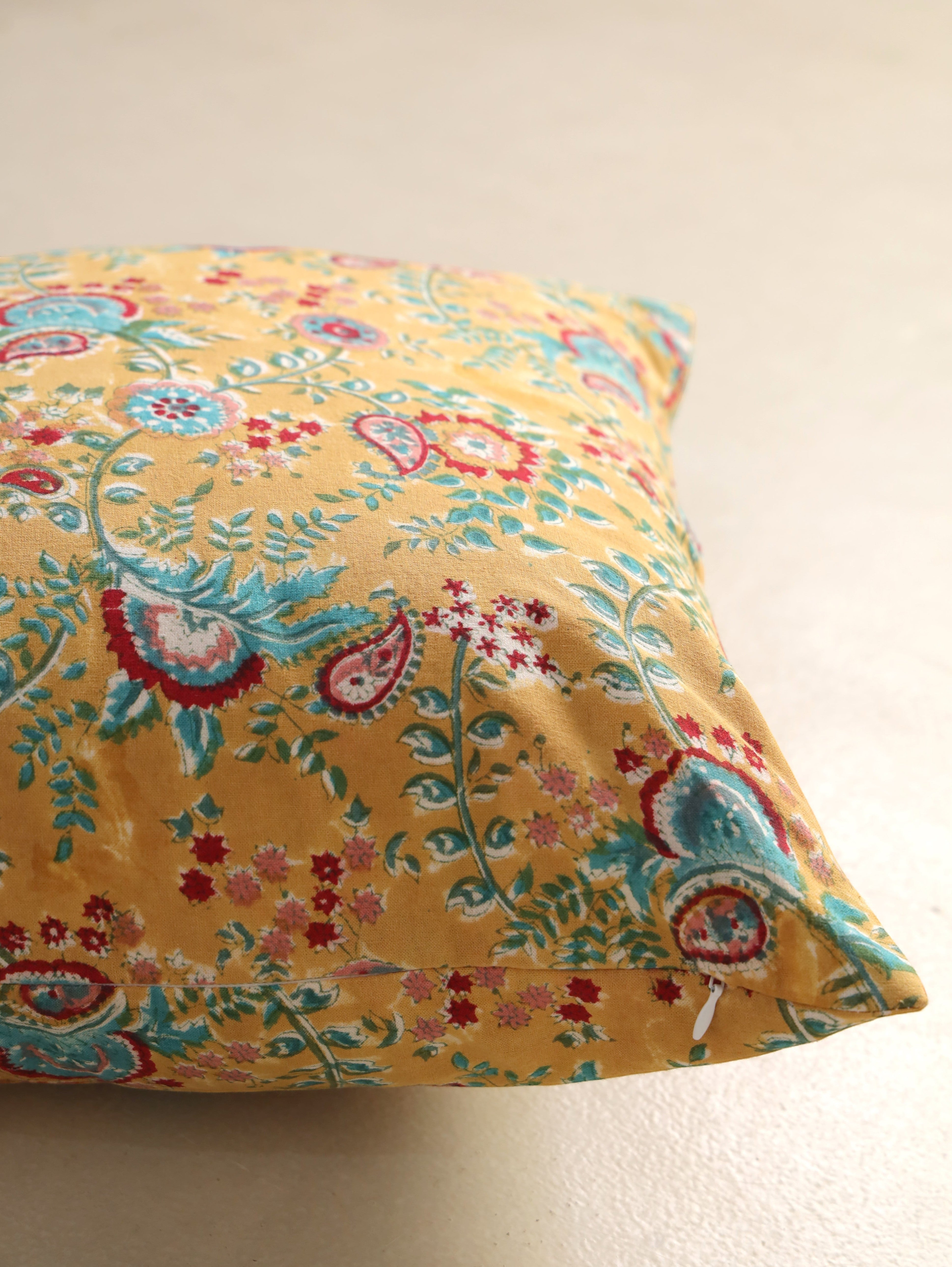 The Block & Bloom mustard cotton cushion cover featuring hand block printed teal and crimson paisley floral motifs.