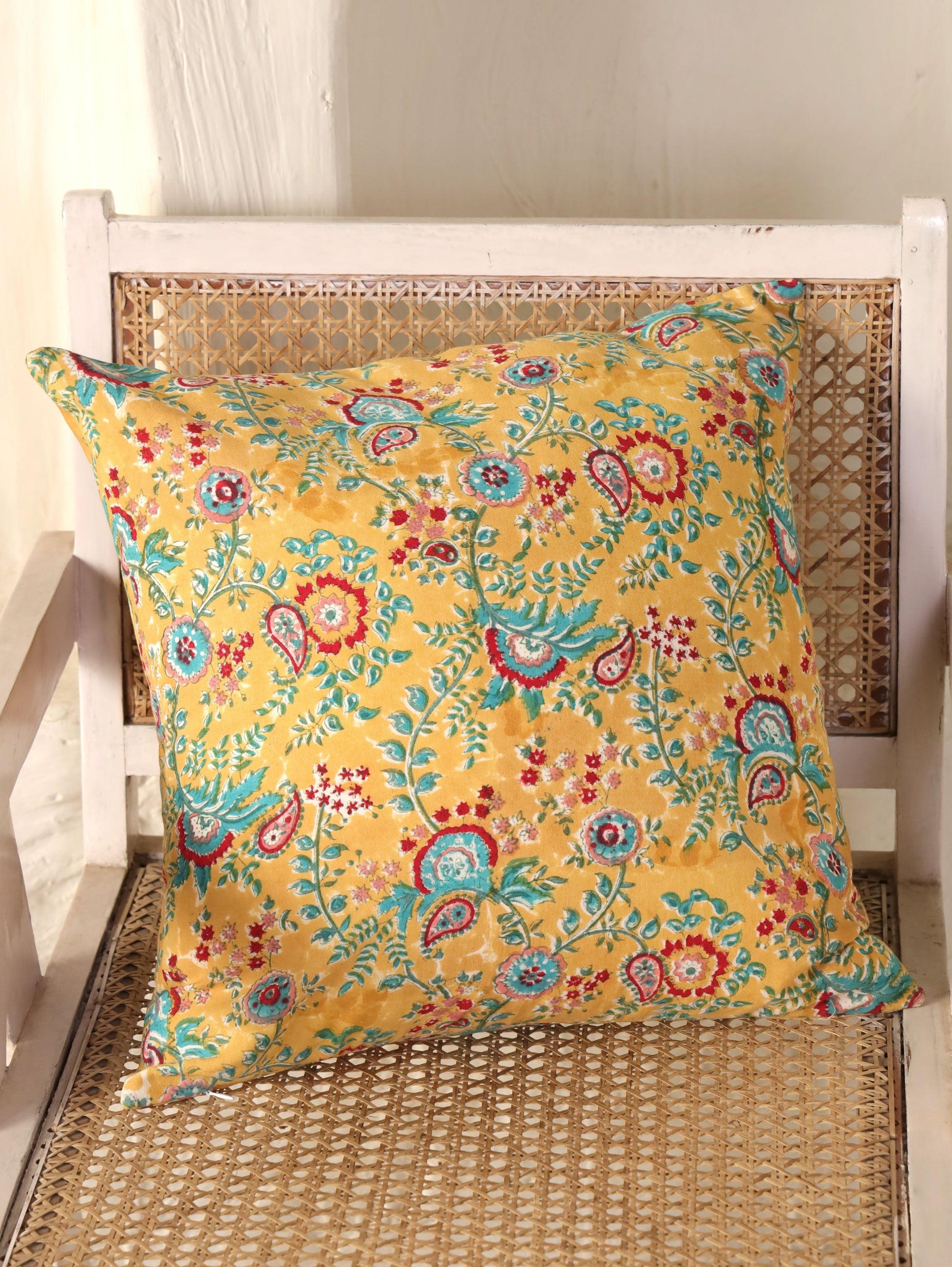 The Block & Bloom mustard cotton cushion cover featuring hand block printed teal and crimson paisley and floral motifs.