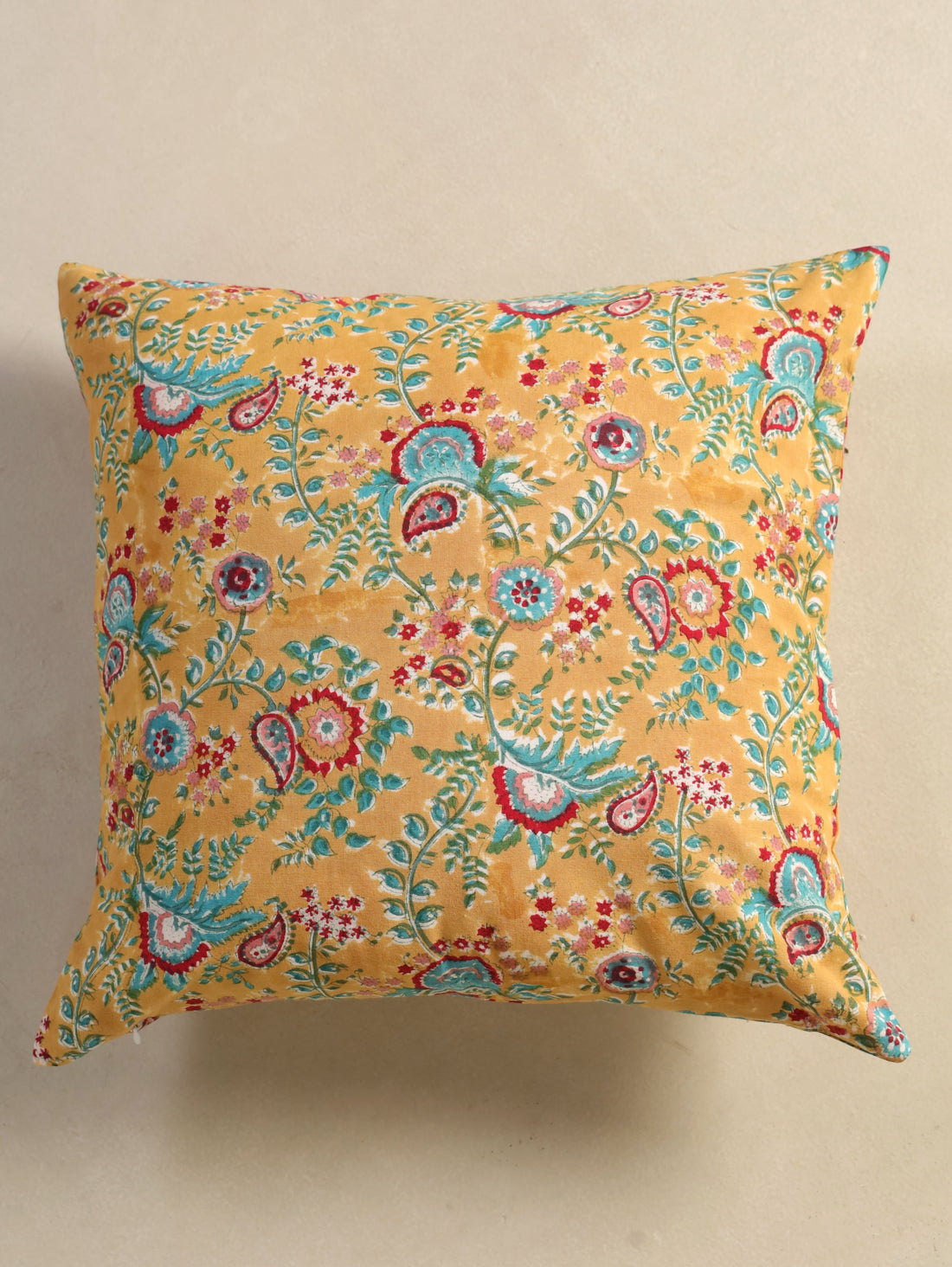 The Block & Bloom mustard cotton cushion cover featuring hand block printed teal and crimson paisley and floral motifs.