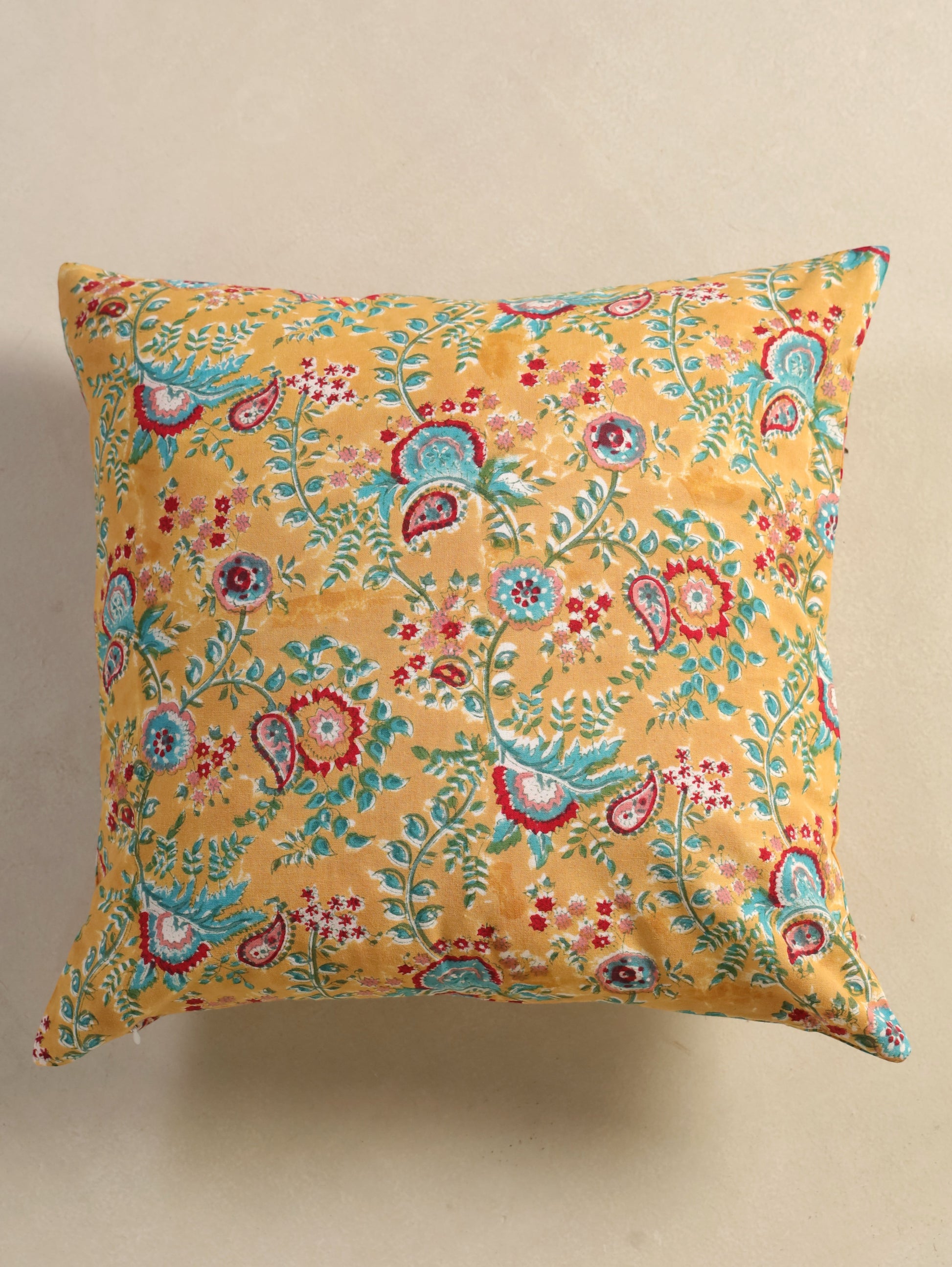 The Block & Bloom mustard cotton cushion cover featuring hand block printed teal and crimson paisley and floral motifs.