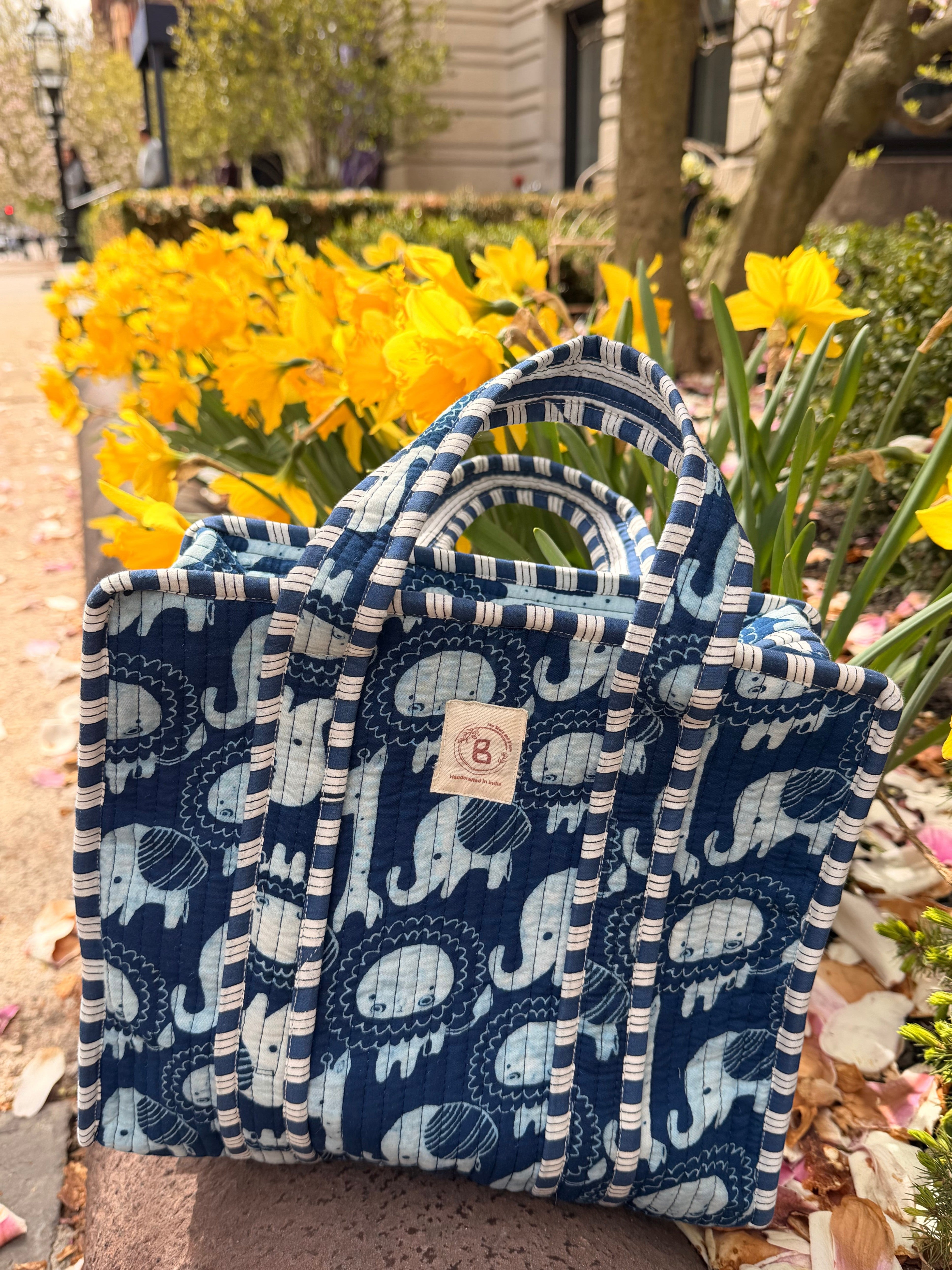 The Block & Bloom navy quilted mini tote with a light blue elephant print, featuring striped handles and brass hardware.