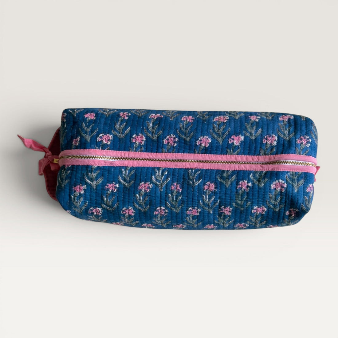 The Block & Bloom navy quilted hair tool organizer bag with pink carnation floral print and pink zipper detail.