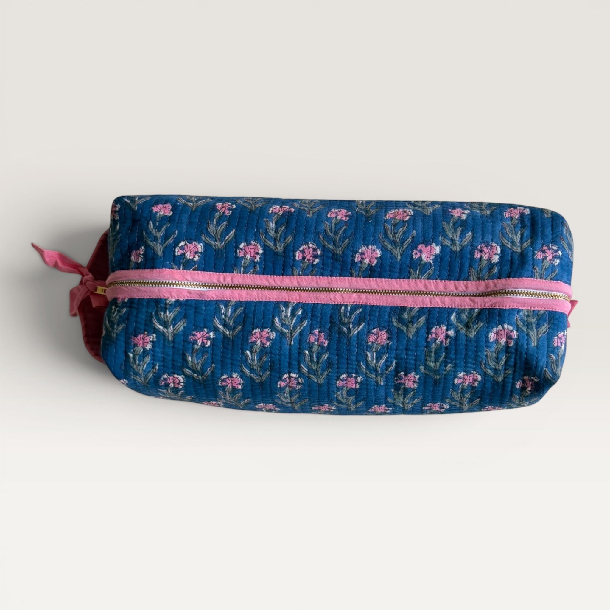 The Block & Bloom navy blue quilted hair tool organizer bag with pink carnation floral print and a pink YKK zipper.